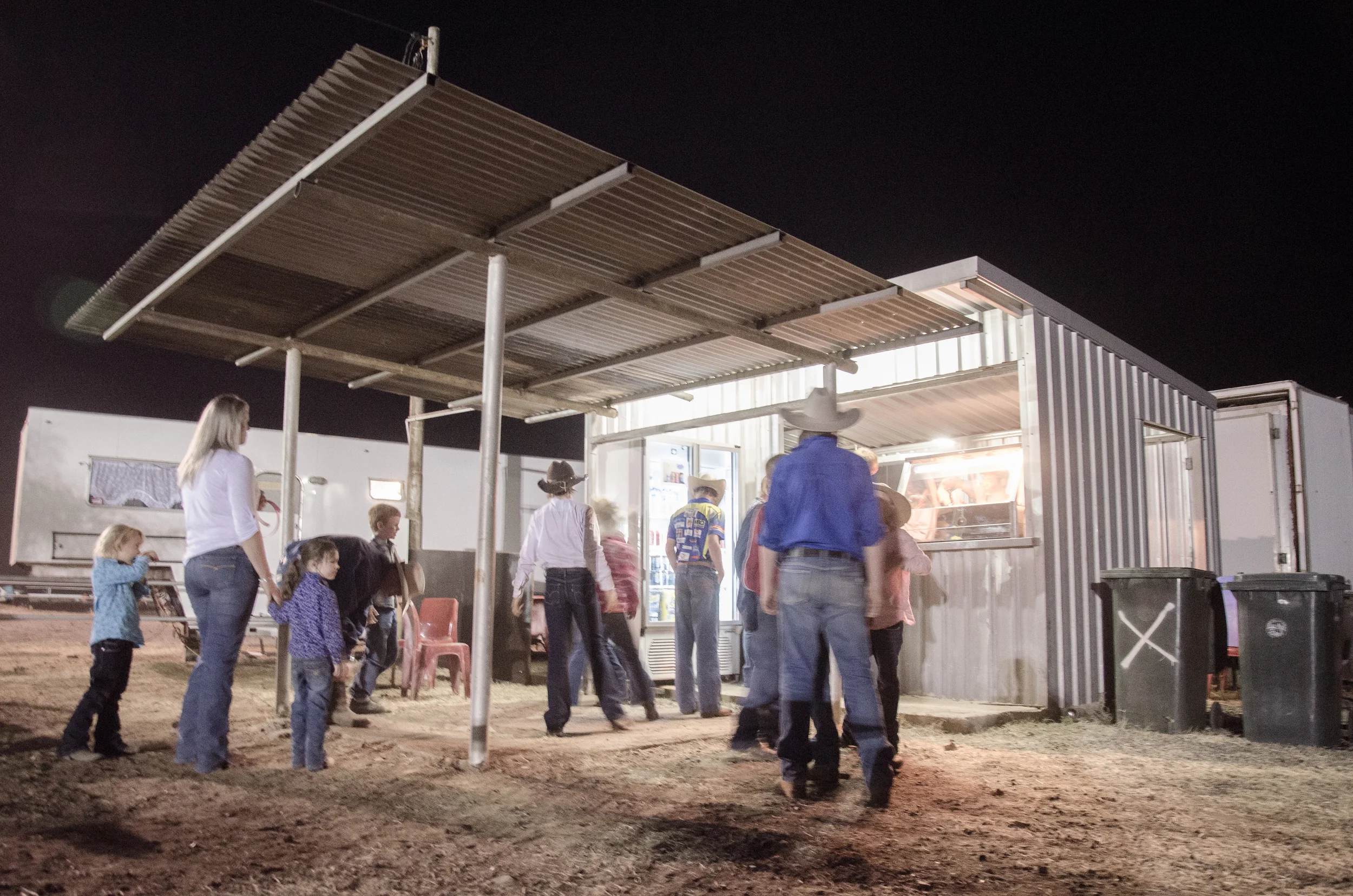   People get in line for a bite to eat before the night campdraft rodeo competition in the Australian heartland.  