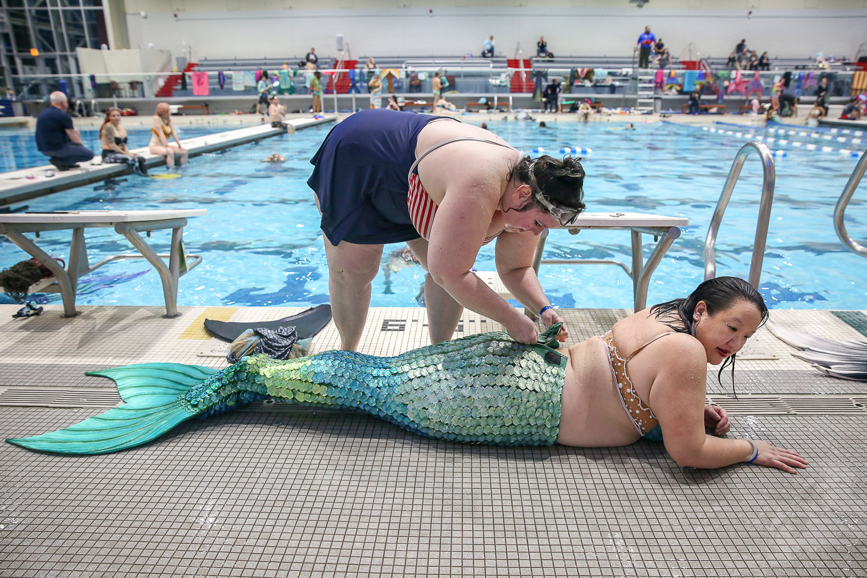 A woman helps Grace Li zip up her mermaid tail at MerMagic Con in Freedom Aquatic and Fitness Center in Manassas, Virginia.
