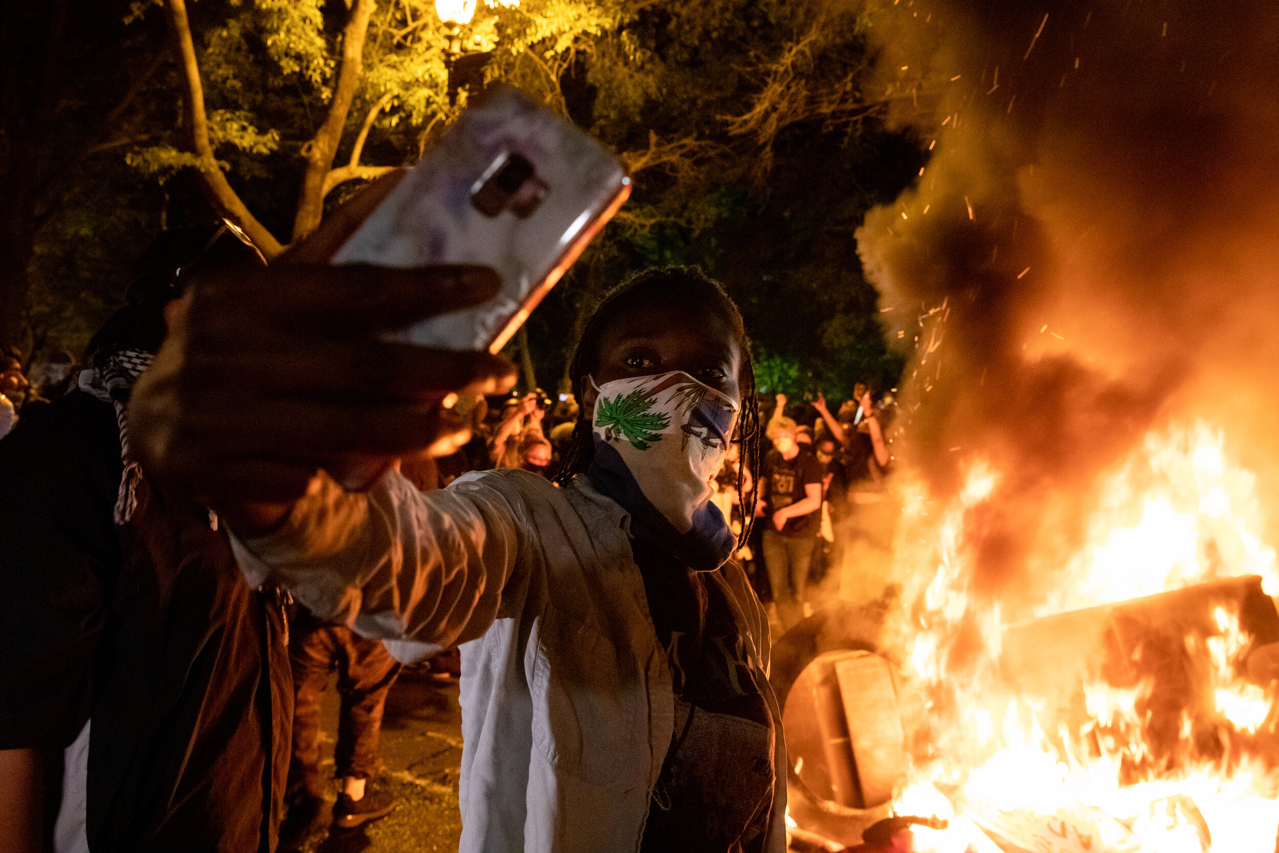 A protestor takes a selfie in front of a fire set during rally against police brutality against unarmed black men following the death of George Floyd, who was killed in Minneapolis, Minnesota, near the White House in Washington, D.C., USA on Sunday,