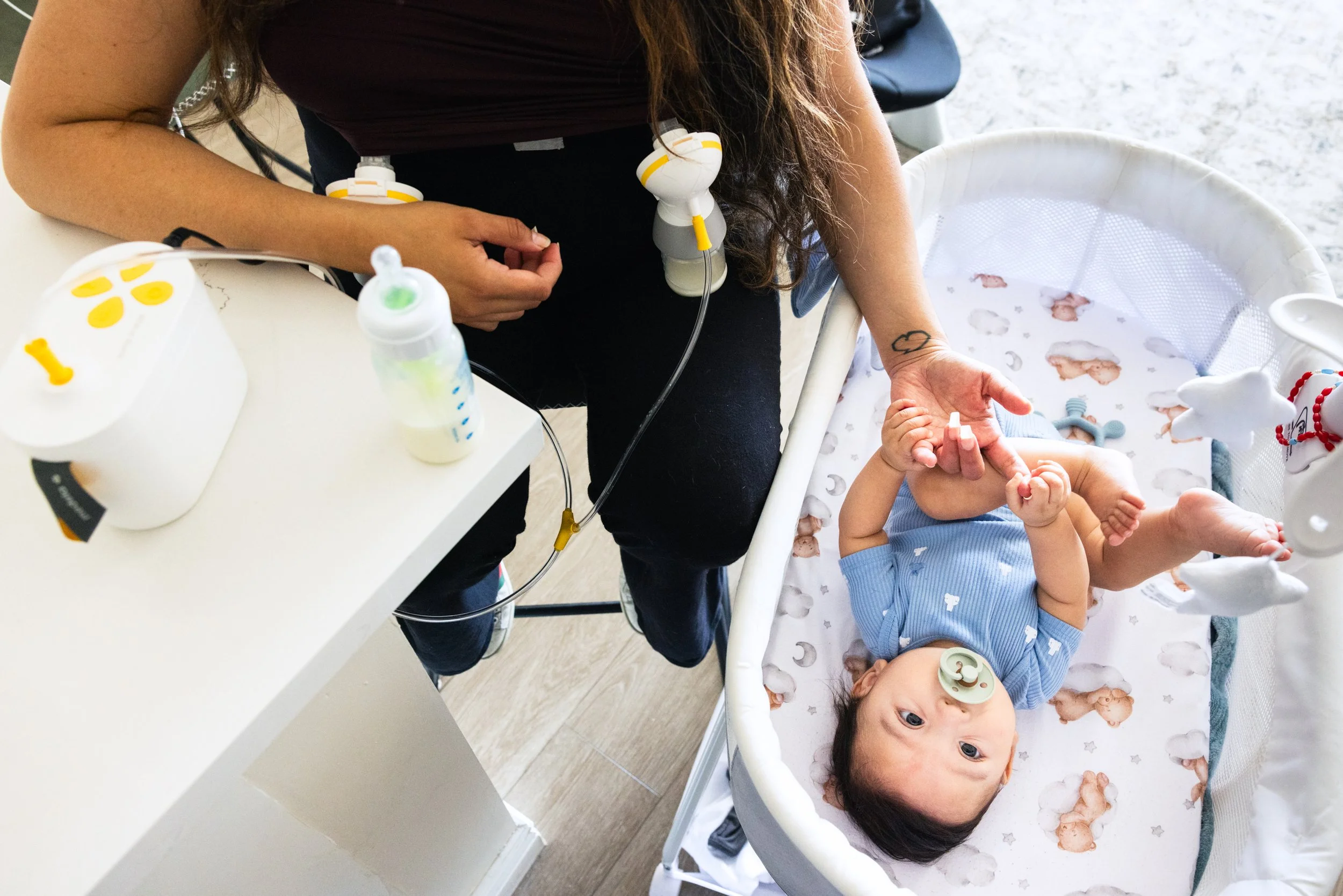 Magali Hernandez pumps breast milk while playing with her son Franco Ramirez at her home in San Francisco on September 24, 2024. Her son Franco, who was born May 5, initially suffered from serious health issues and was hospitalized in a neonatal int