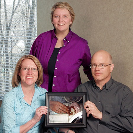 Sona with friends JoAnn and Darrin, holding a photo of their sweet Brighid