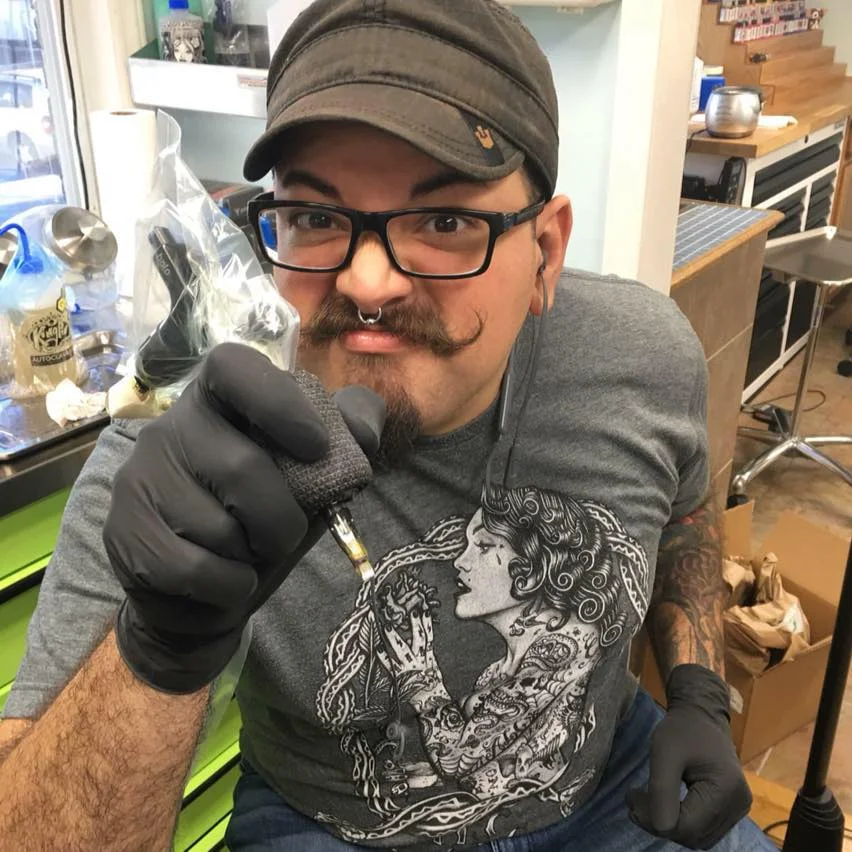 Noel Michel moved to NC from CA with his family when he was just a little jalapeno. He grew up in the Lenoir area and has been in Mooresville for the last few years. Noel started tattooing in 2008 and is the baby of the shop. Noel joined team 13 in 2013 and has been building an ever growing fan base since then. Noel is known for his bright color, thin lines and award winning smile!