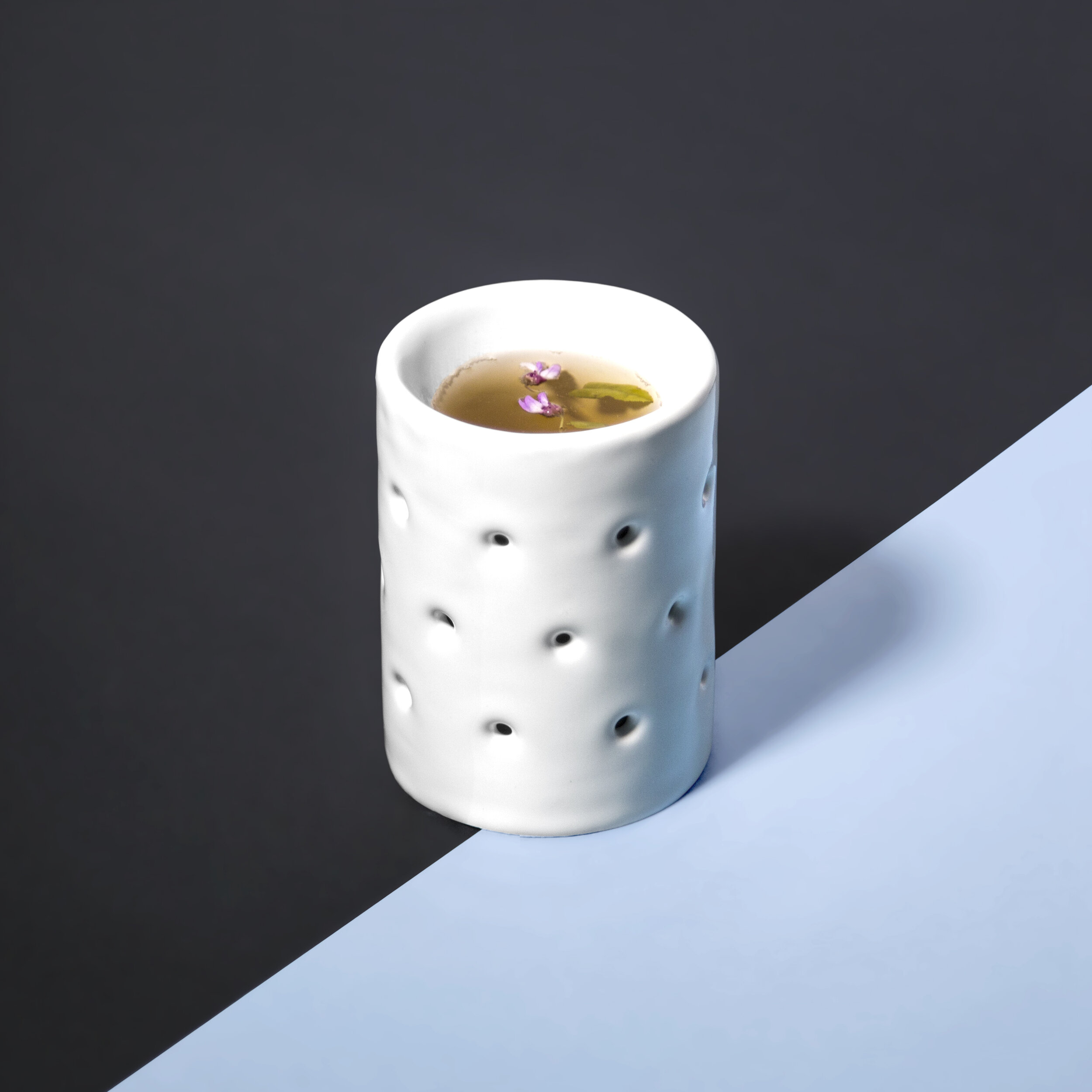 This pair of ceramic drinking vessels play with double-walled construction to accommodate hot beverages.