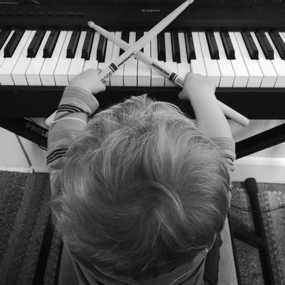 Elliott with drum sticks on piano.jpg