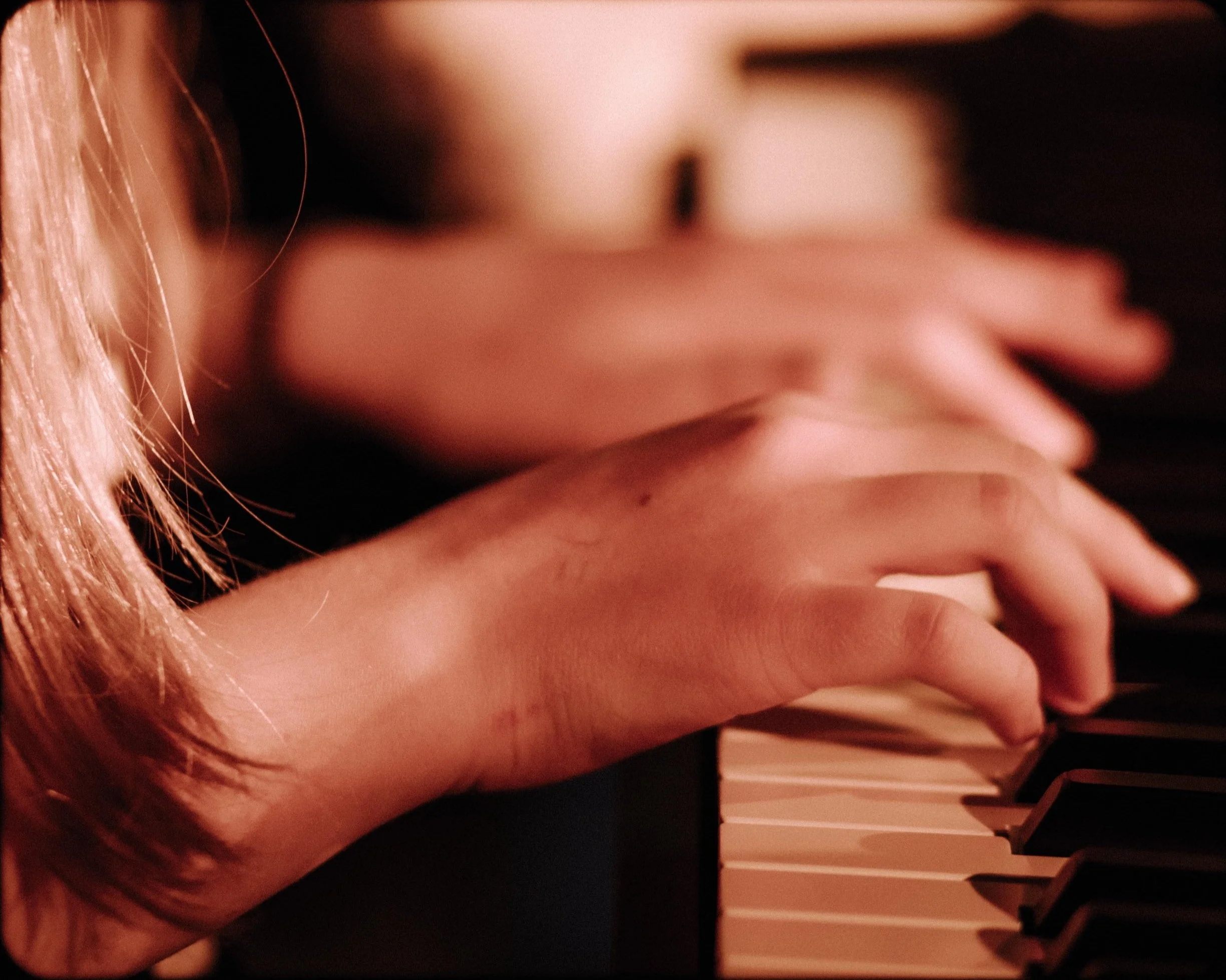 Close-up of a person's hand playing piano keys, with the focus on the fingers and the keyboard. Piano lessons.