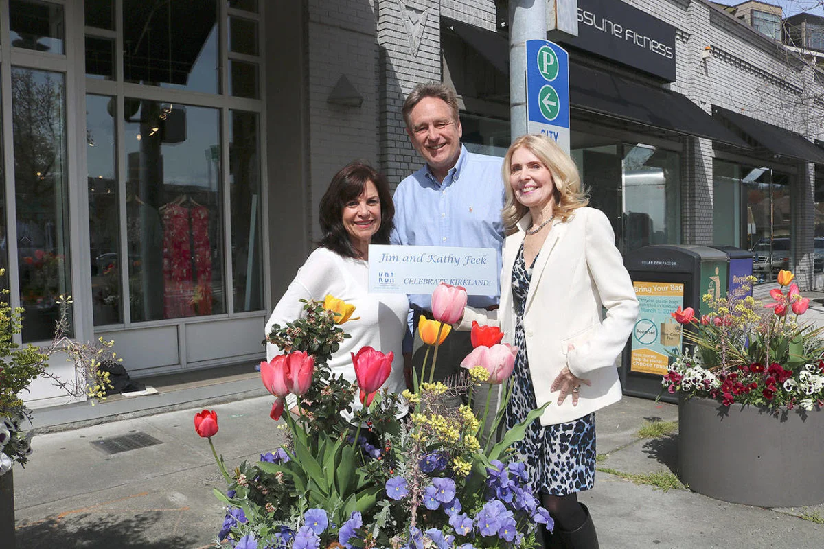 From left: Flower Pot program chair Anne Hess, KDA executive director Michael Friedline, and Flower Pot program chair Kathy Feek pose near flower pots in downtown Kirkland with a sample of the new plaques. Stephanie Quiroz/staff photo.