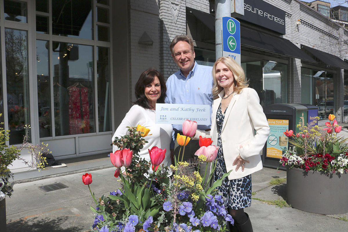 From left: Flower Pot program chair Anne Hess, KDA executive director Michael Friedline, and Flower Pot program chair Kathy Feek pose near flower pots in downtown Kirkland with a sample of the new plaques. Stephanie Quiroz/staff photo.