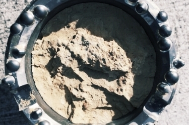 Sonic drill bit with 100mm siltstone core sample. We can collect soil samples up to 230mm in diameter.
