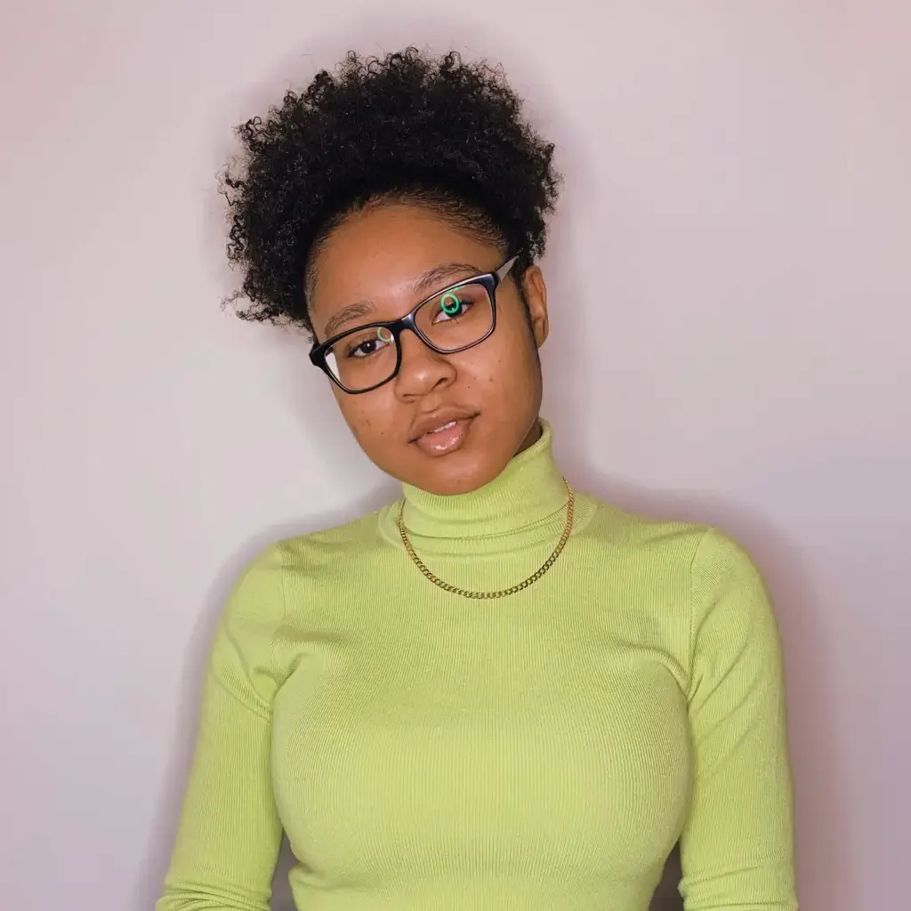 Woman wearing a yellow turtle neck and glasses