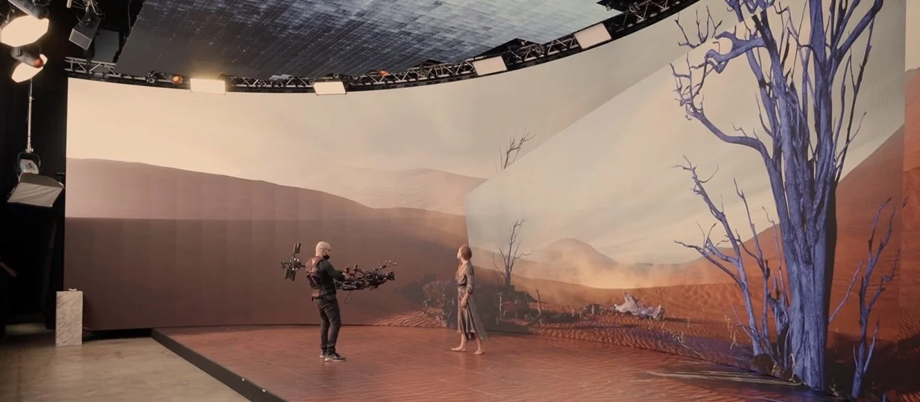 Actor filmed on an LED wall stage showing a desert landscape during virtual production.