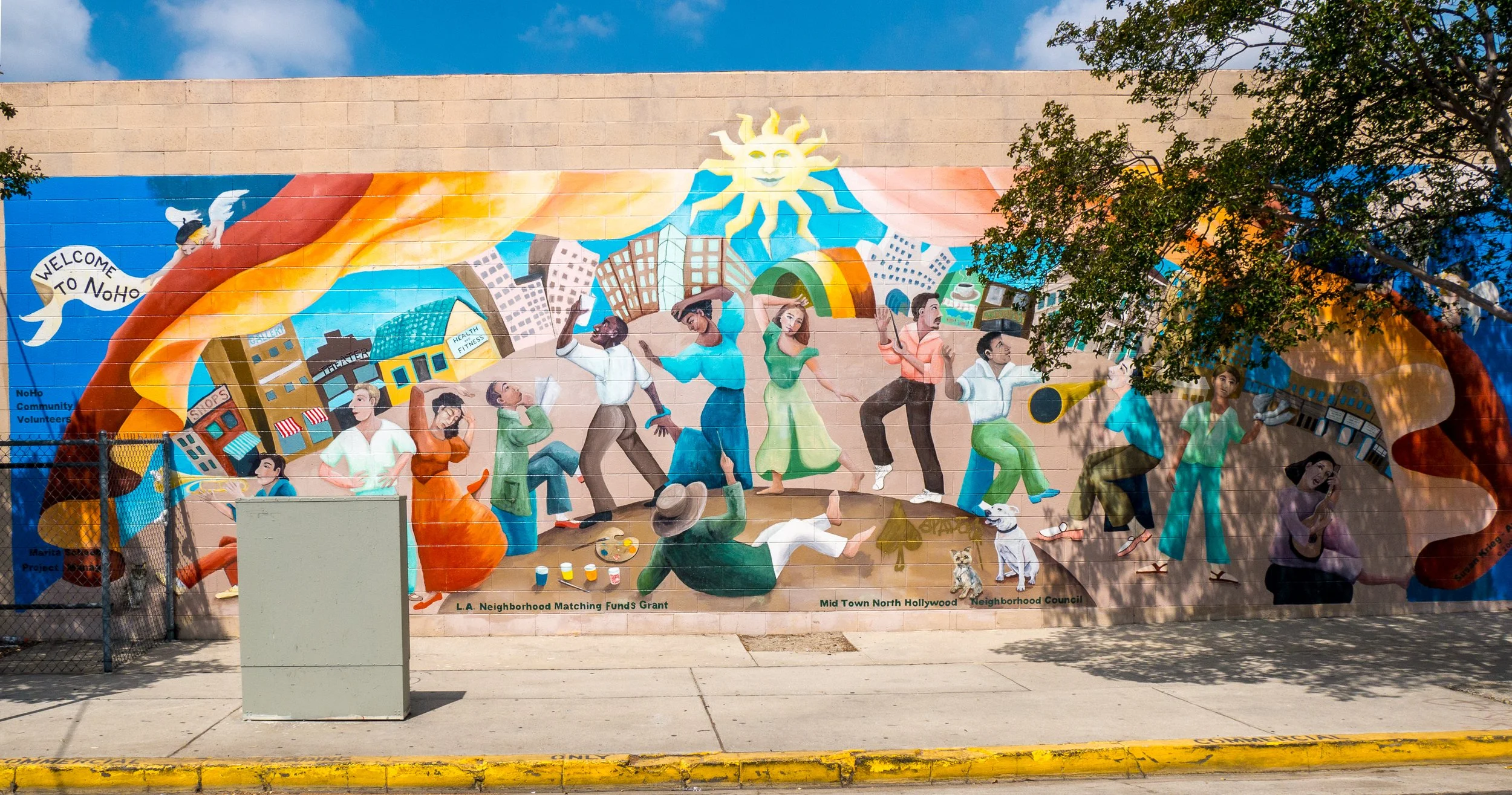 Colorful painted mural in naturalistic-style featuring people of different backgrounds engaging with each others, dancing, and playing music.