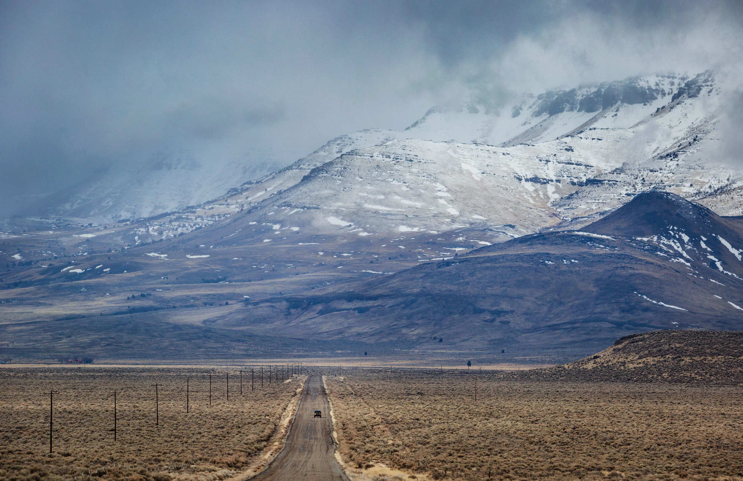 Lone car on the dirt road heading into the snowy Steens Mountains in Southern Oregon. 