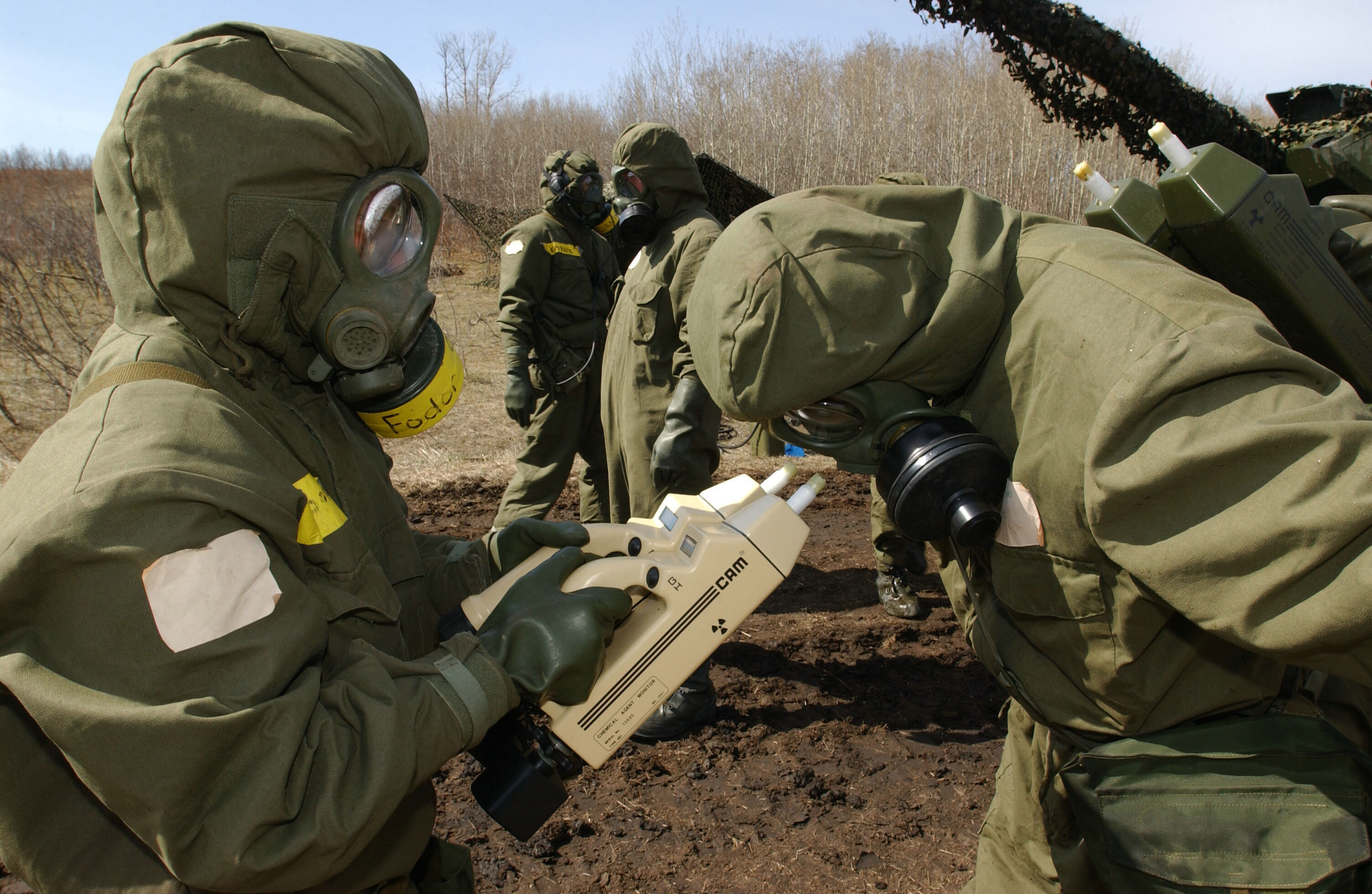 Private Jennifer Fodor, a member of 2 General Support Battalion from Petawawa, Ontario, checks Warrant Officer Benson for chemical contamination with two chemical agent monitors (CAM) during a decontamination operation. (Combat Camera)