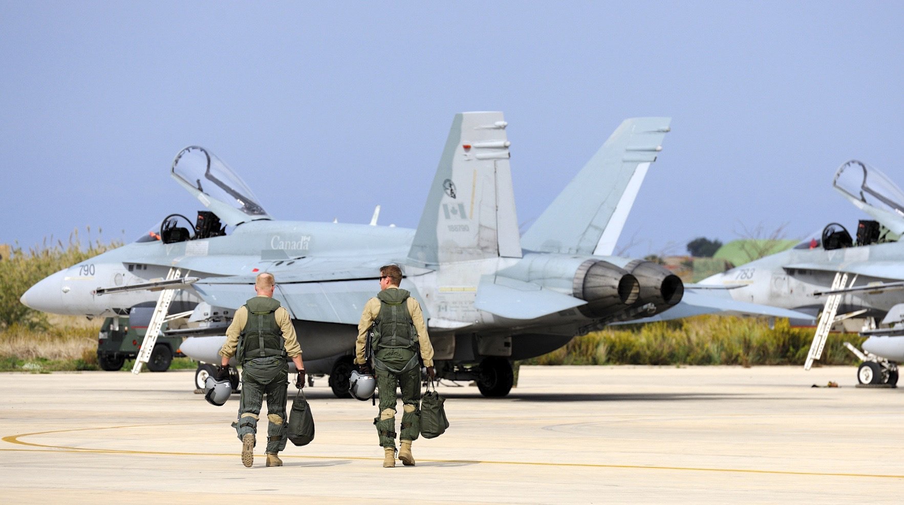 Two CF-18 Hornet pilots make their way to the flight line to return to Canada from Trapani, Italy on November 2, 2011. The Canadian pilots flying sorties over Iraq as part of Operation IMPACT adhere to a strict routine, working on a 24-7 rotation. (Combat Camera).