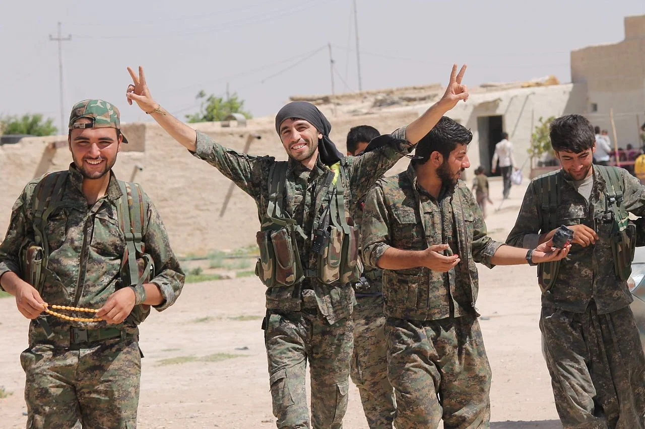 Members of the YPG (People’s Protection Units) Kurdish militia, who have recently been joined by Canadian volunteers eager to fight against ISIS. Under the Conservative government's planned travel plan, Canadian nationals seeking to fight as civilian volunteers may find themselves running afoul of the law, especially given the recent hostilities between Turkey - a NATO ally - and the Kurdish revolutionaries, who include in their numbers the PKK, a designated terrorist organization. (Wikipedia)