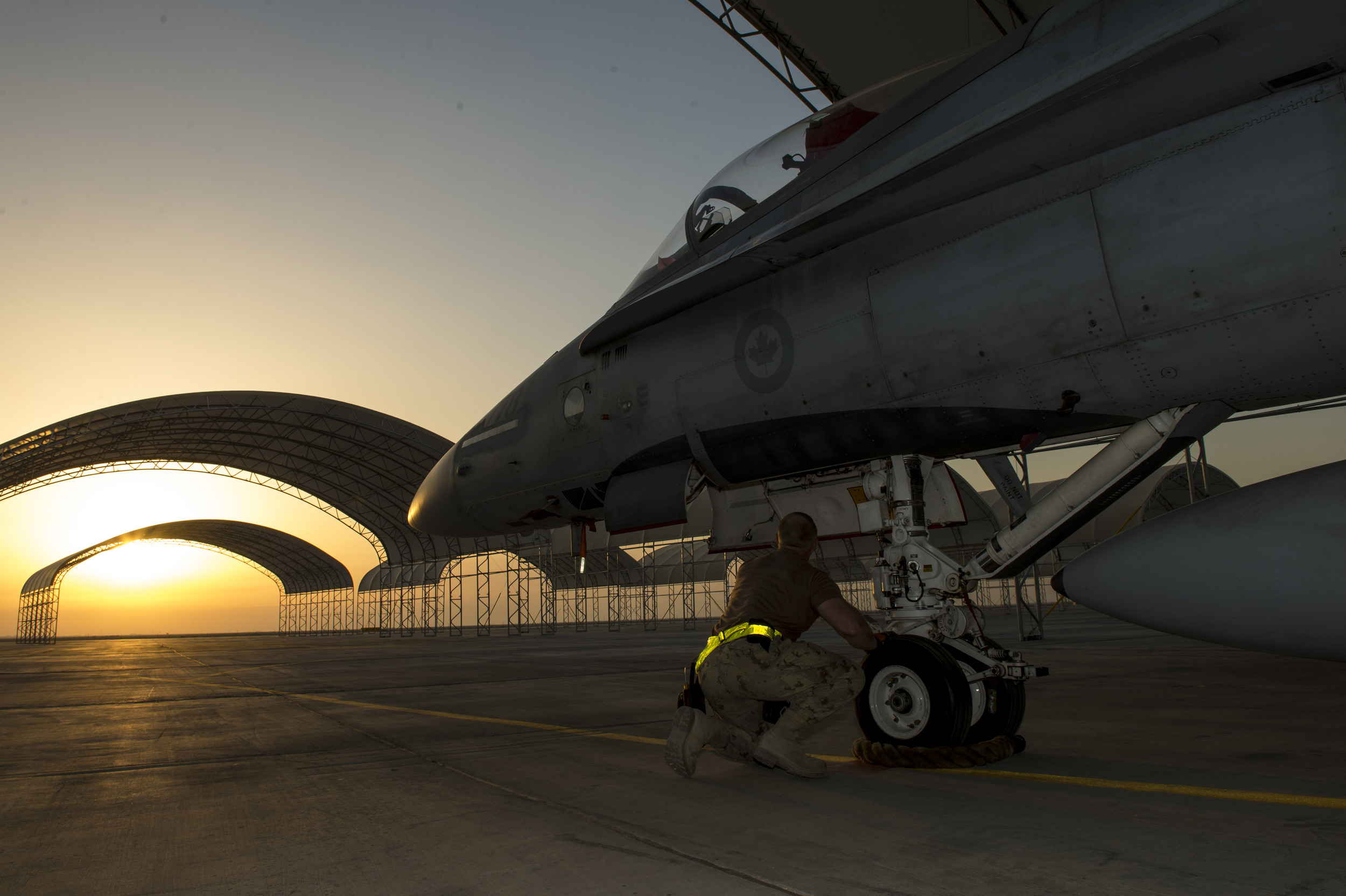 An aircraft technician from Air Task Force – Iraq inspects the nose landing gear of a CF-188 Hornet aircraft at the Camp Patrice Vincent flight line, in Kuwait during Operation IMPACT on December 11, 2015. (combat camera)