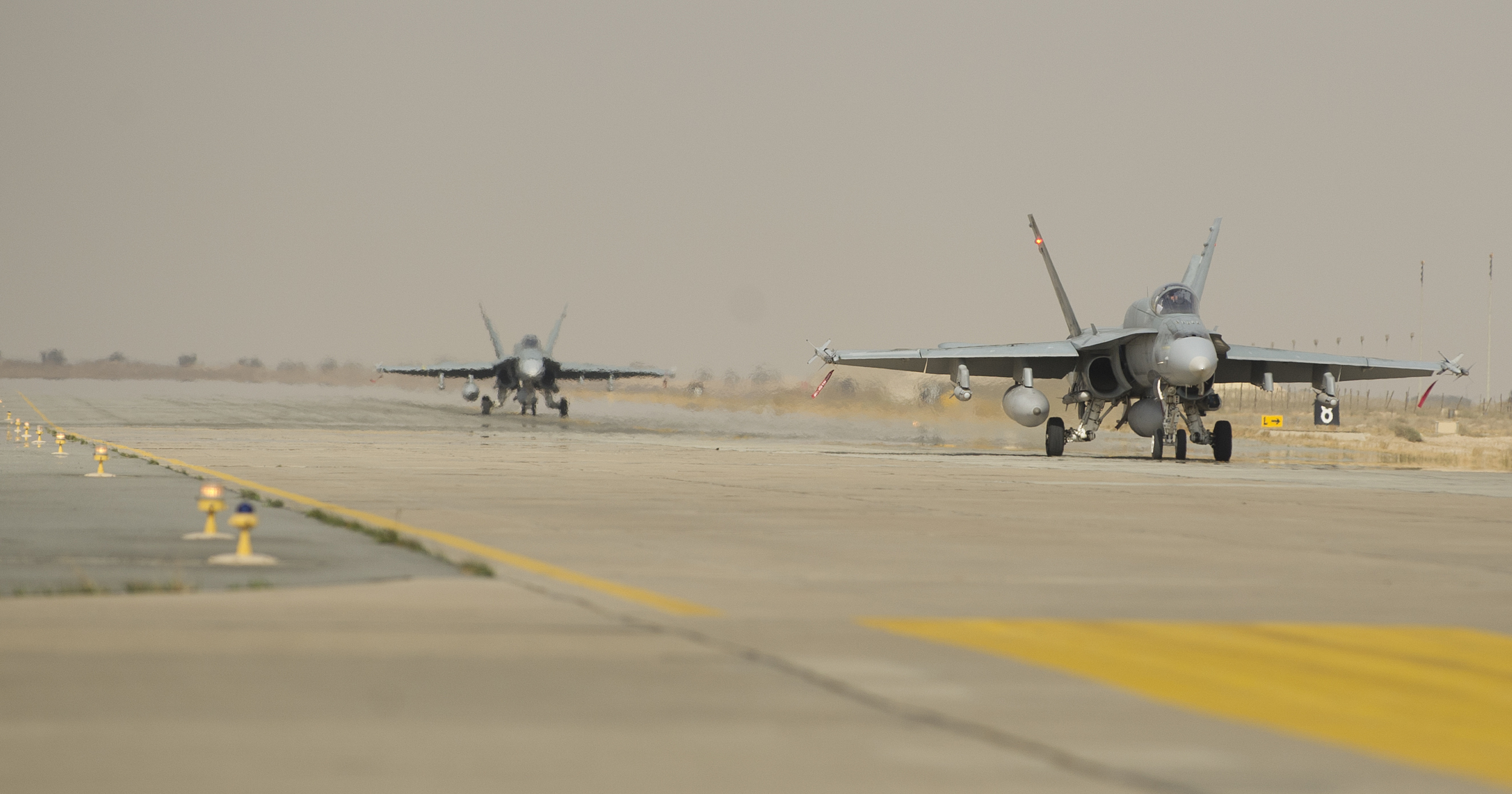 Two CF-18 Hornet fighter jets taxi out to the arm/disarm area in preparation for their next mission at Camp Patrice Vincent, Kuwait during Operation IMPACT on January 17, 2015.
