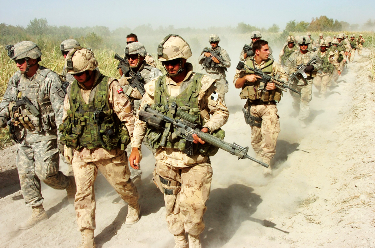 Under heavy security, the commander of the Multi-National Brigade South, BGen David Fraser (center), tours an area occupied by Canadian and other allied forces in the Panjwaii District west of Kandahar City in September 2006. His is flanked by Chief of Staff Colonel Williams (left) and Commanding Officer Task Force 3-06 Battle Group Lieutenant Colonel Omer Lavoie (right). (Combat Camera)