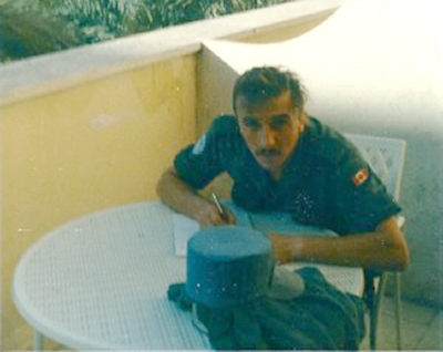 Frank Reid`s roommate at the Ledra Palace Hotel writes a letter home. Note his hat on table. Every night they would starch them and stretch them over a large fruit can to give them shape. Then they would sweat in the hot sun and the starch would run out of the hat and down their foreheads adn run in their eyes and burn them. (Frank Reid)