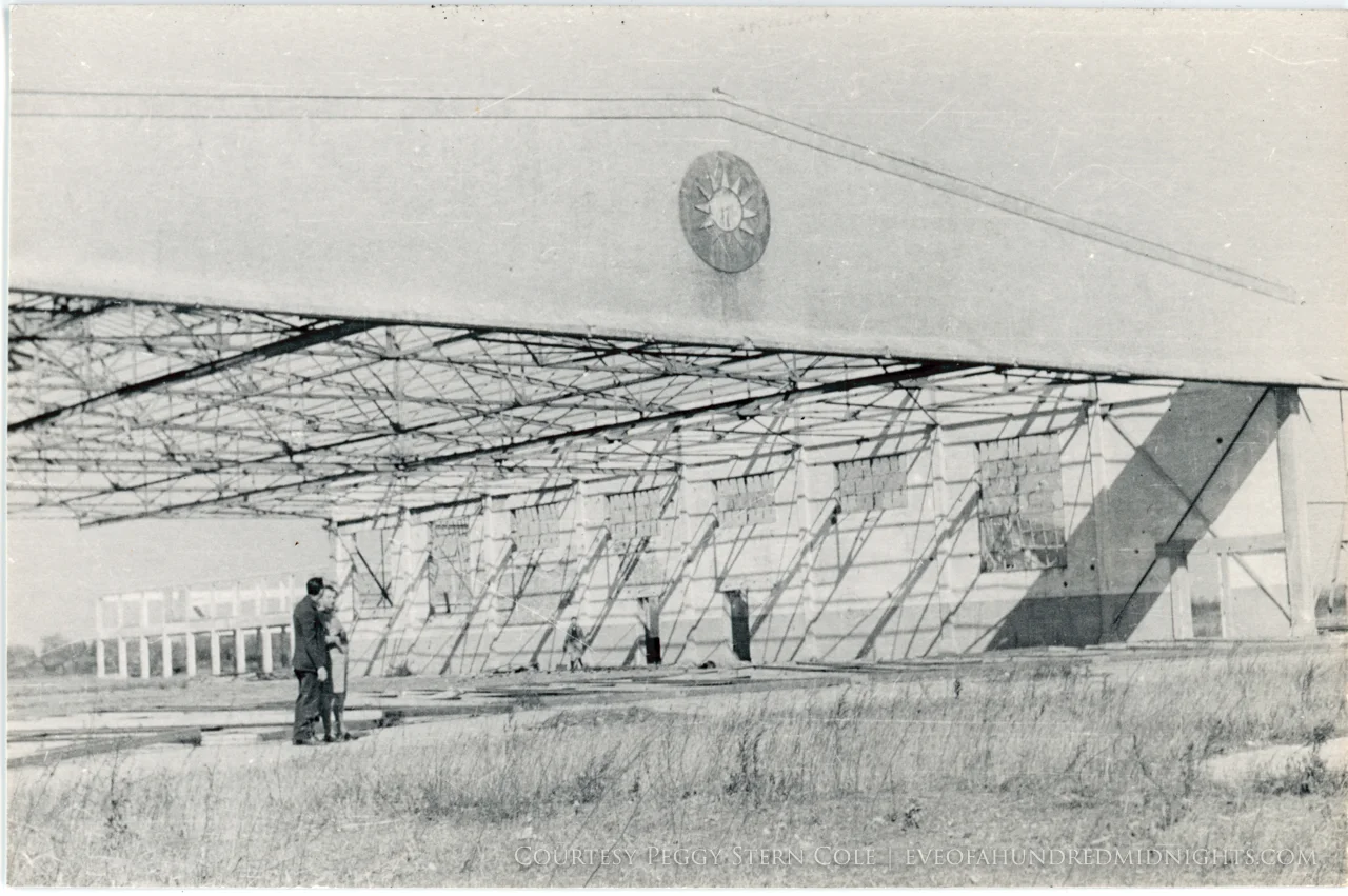 Abandoned RoC hangar with two people in front.jpg