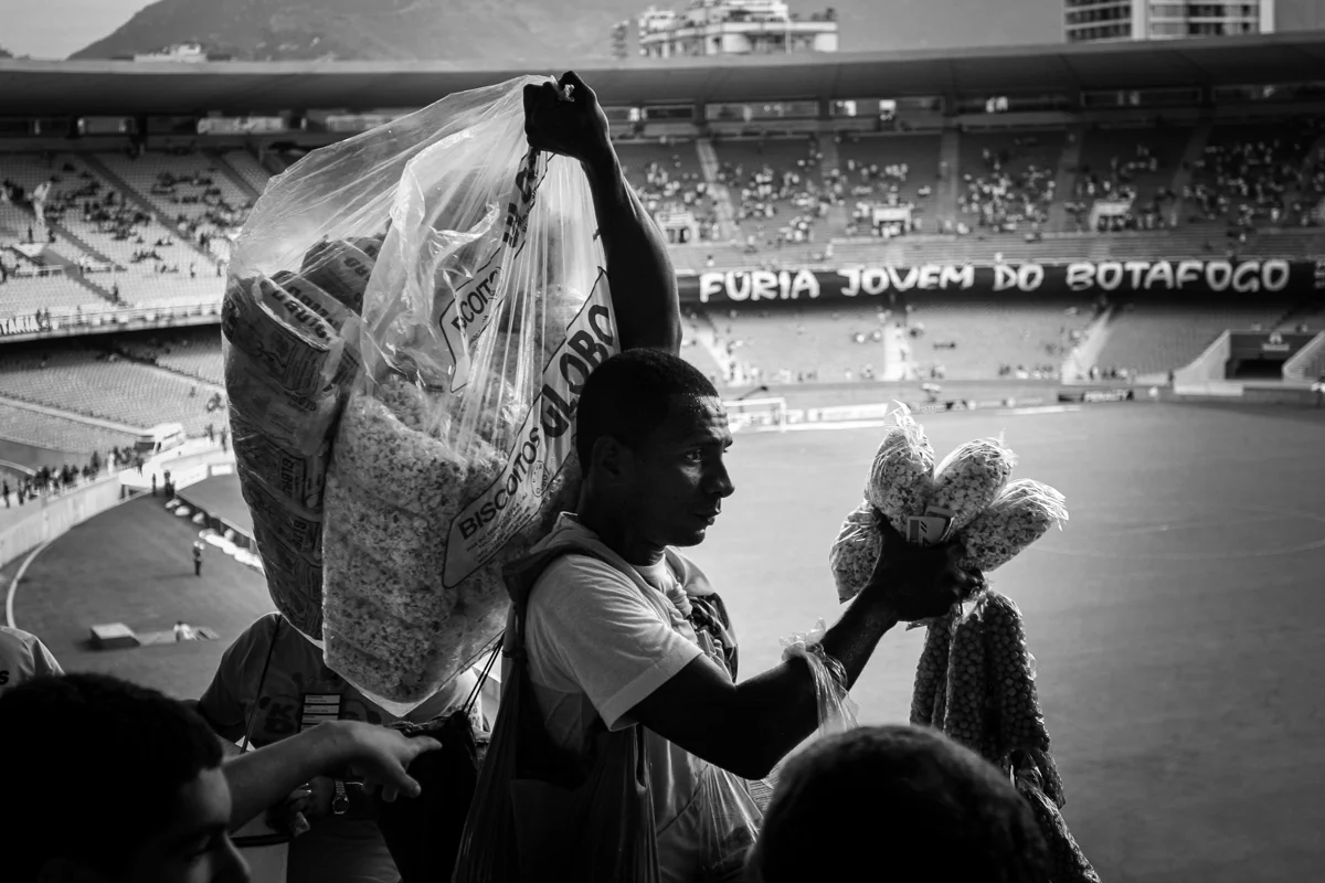 A man is selling popcorn and nuts as the stadium is beginning to fill up with spectators.
