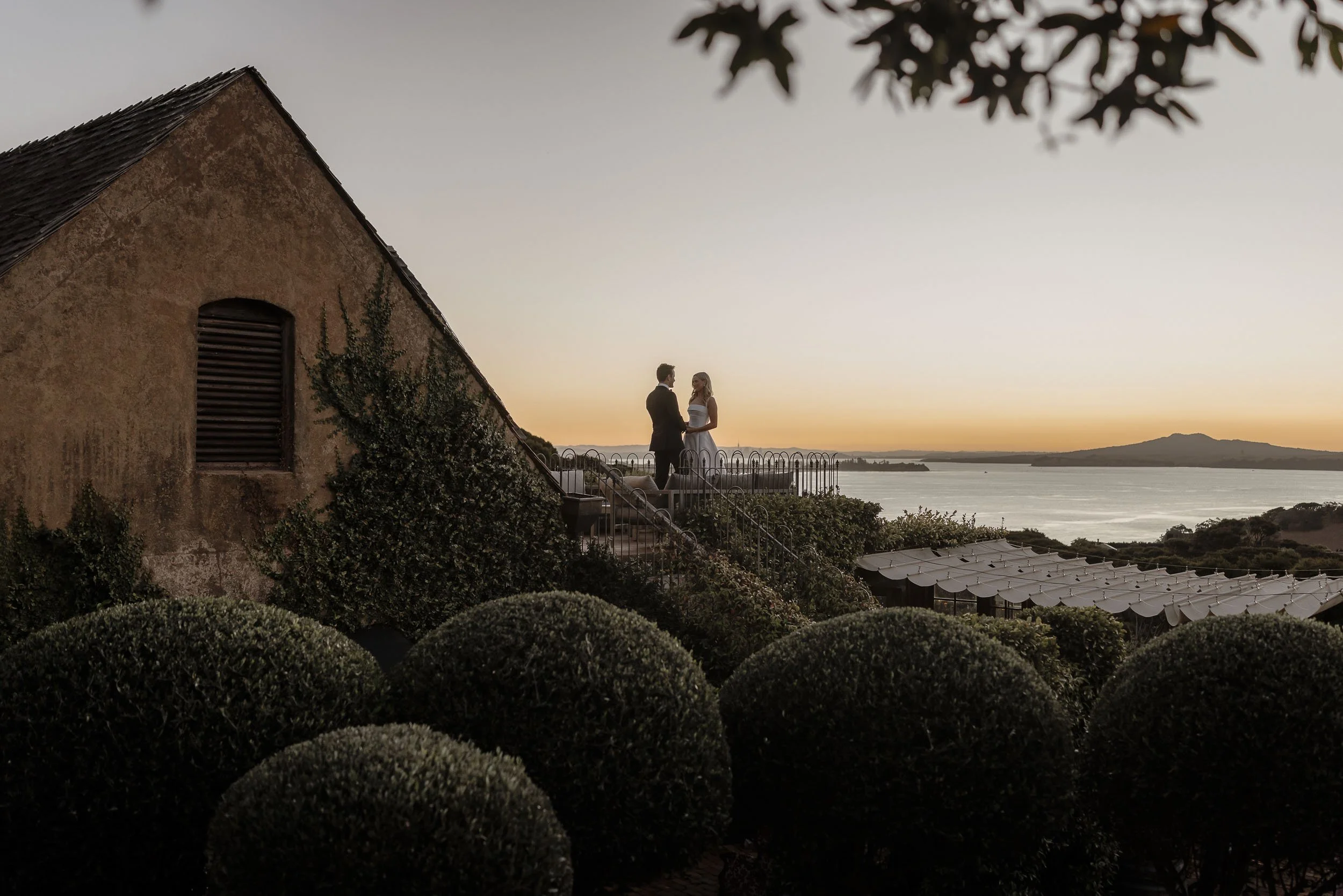 Couple embrace on sunset during their wedding day, celebrated at Mudbrick Estate and Vineyard, Waiheke Island, New Zealand
