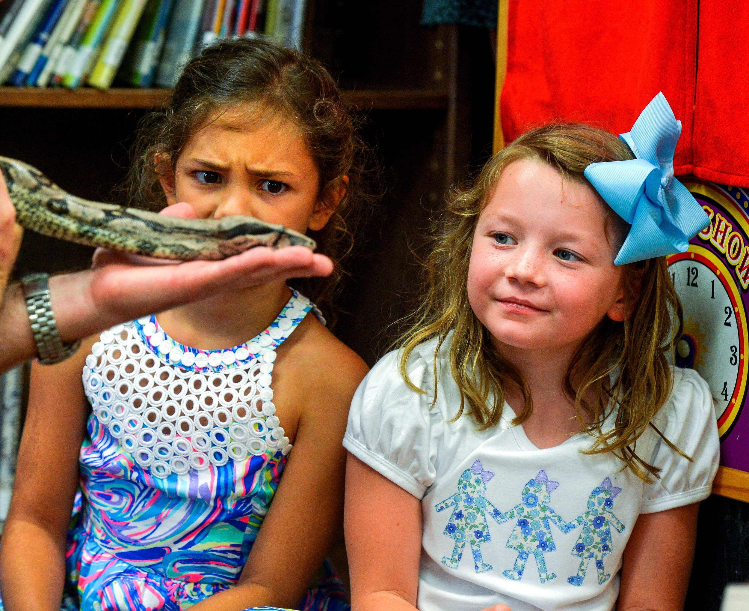 Alexis White, 6, left, and Mary Hyatt Adams, 6, have different reactions as they look at a red-tailed boa constrictor during the Echoes and Howls program presented by the Natural History Educational Company at Decatur Public Library on June 13, 2018.