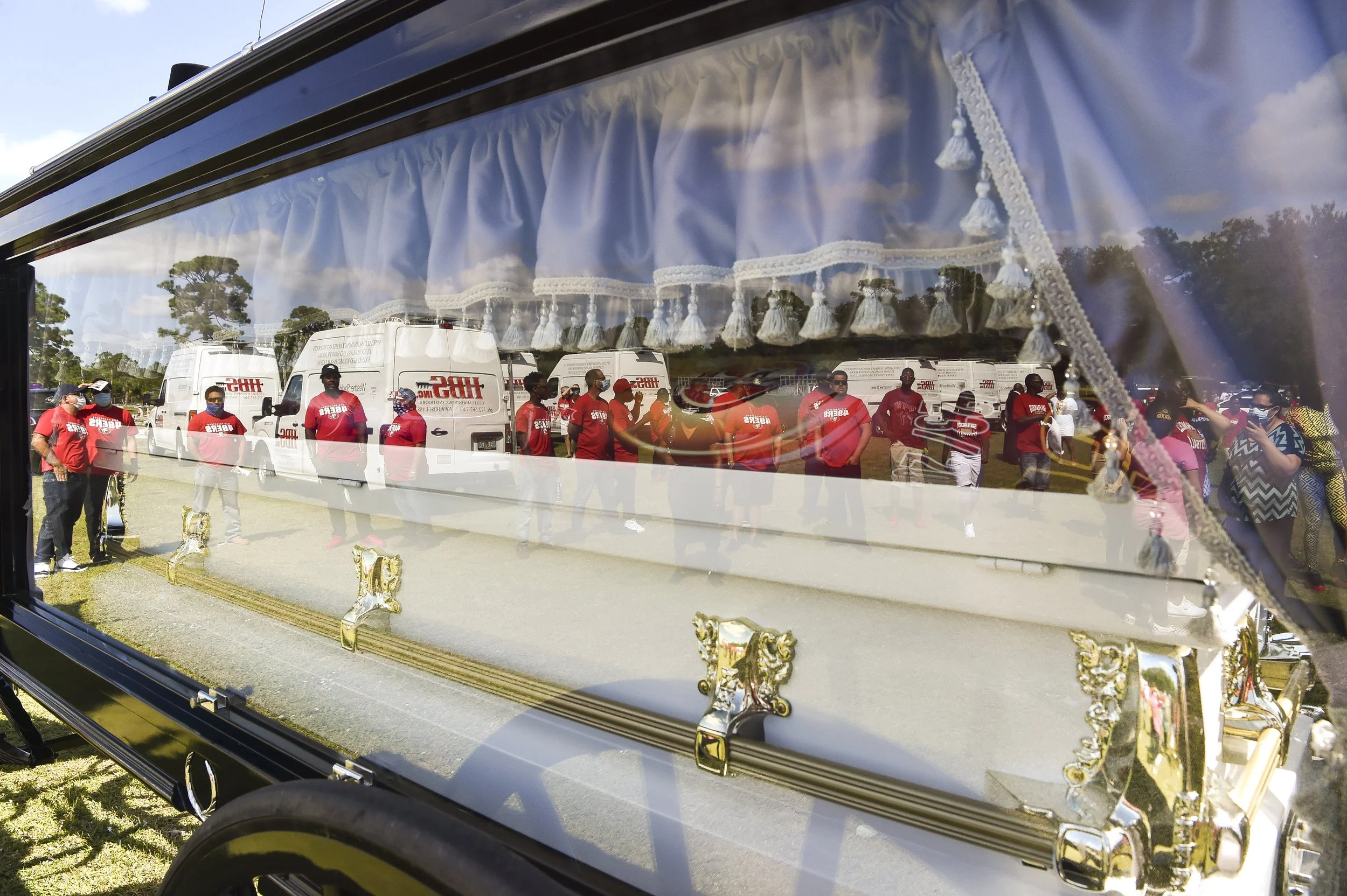  Jesse Eugene Parker's HBS Glass co-workers and work trucks are seen in the reflection on the glass case carrying Parker's casket during his ceremony of life service on Saturday, Oct. 2, 2021, at Gifford cemetery in Indian River County. Parker, 53, r
