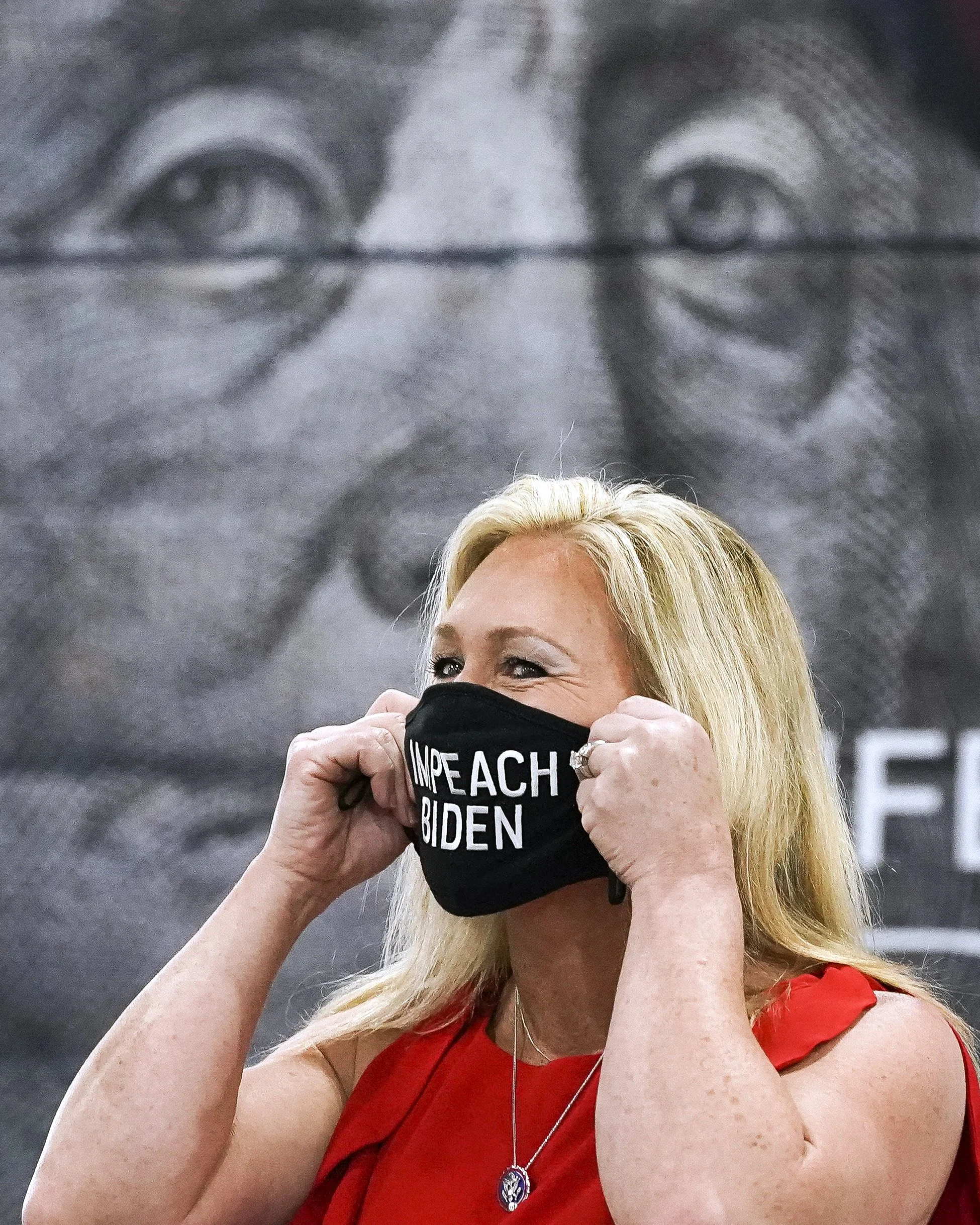  U.S. Rep. Marjorie Taylor Greene holds a "Impeach Biden" mask to her face before speaking to a crowd of about 400 people gathered at the Indian River County Fairgrounds for the “America First Rally” Saturday, April 24, 2021, in Indian River County. 
