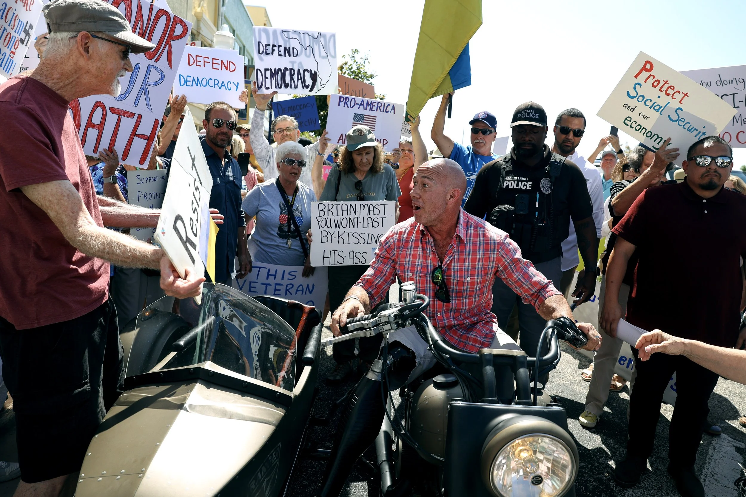  U.S. Rep. Brian Mast speaks with Bob McCrady, of Port St. Lucie, during a protest demanding a town hall with Mast, Friday, March 14, 2025, in downtown Stuart. The rally was organized by Martin County Democrats. The organization posted on their websi