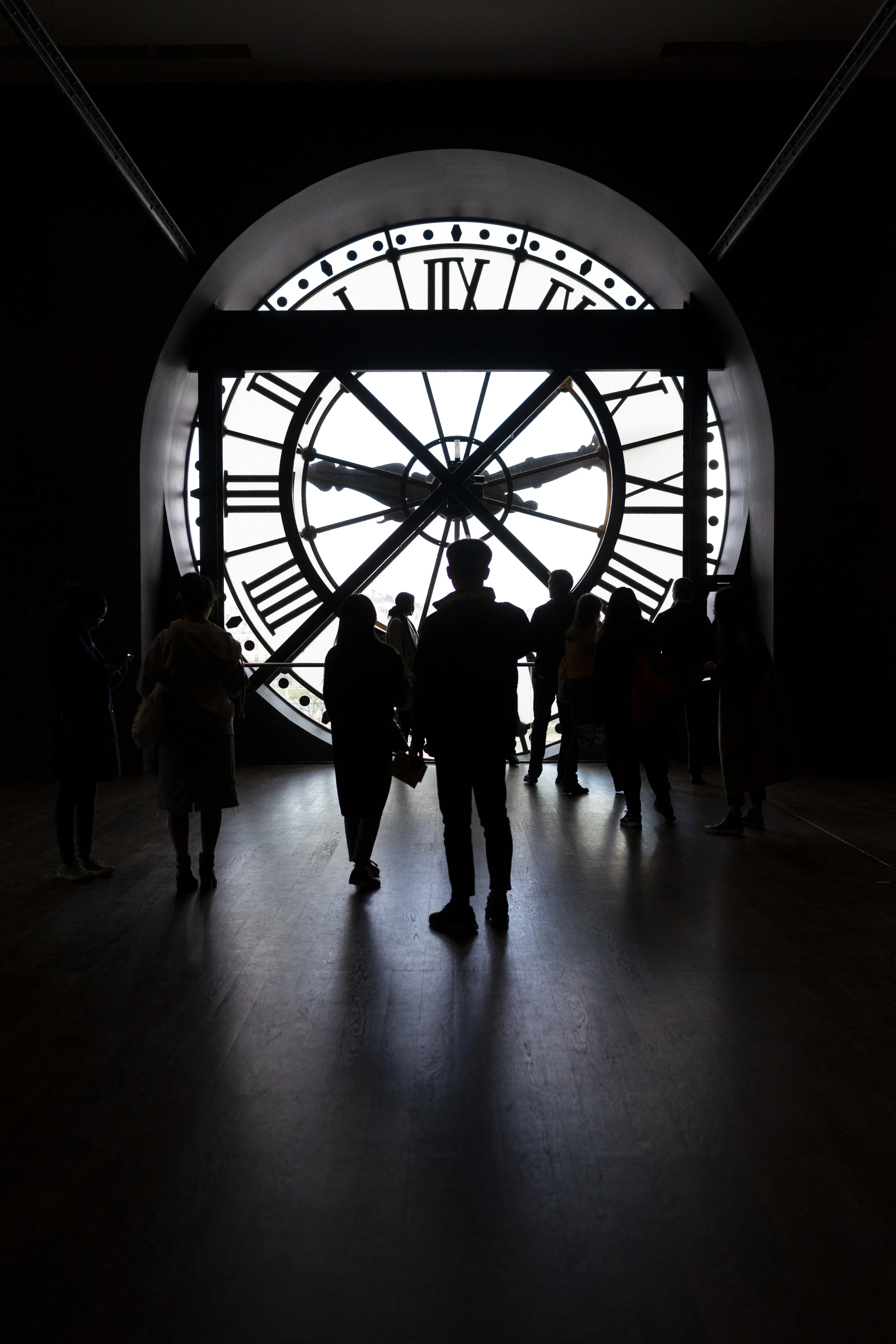 A group of visitors at the Musée d’Orsay are silhouetted as they look through the clock face to see the city of Paris. (Elise Marie Photography)