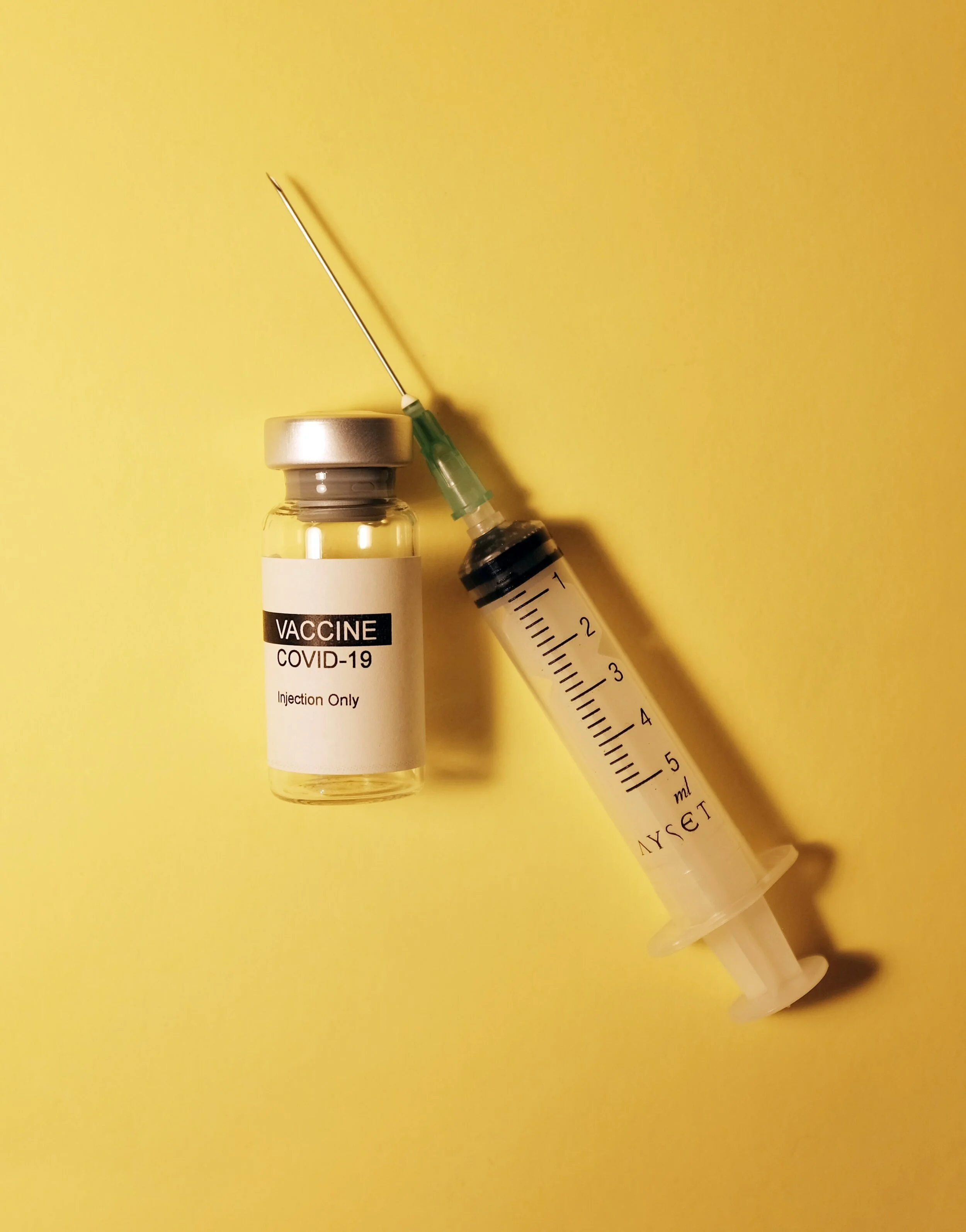A photograph of a COVID-19 vaccine vial and syringe.