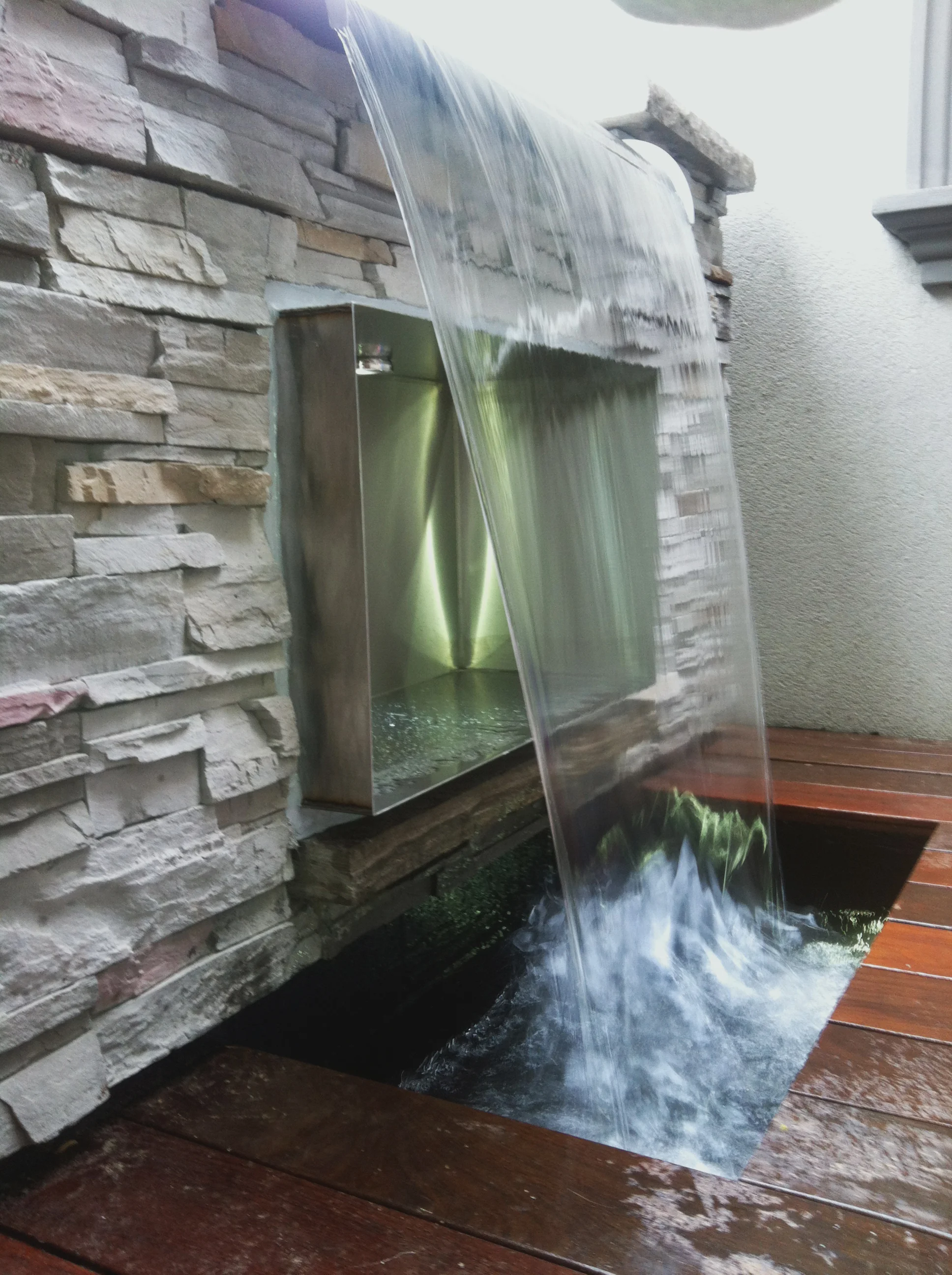 This waterfall feature is incorporated into the deck of this small terrace