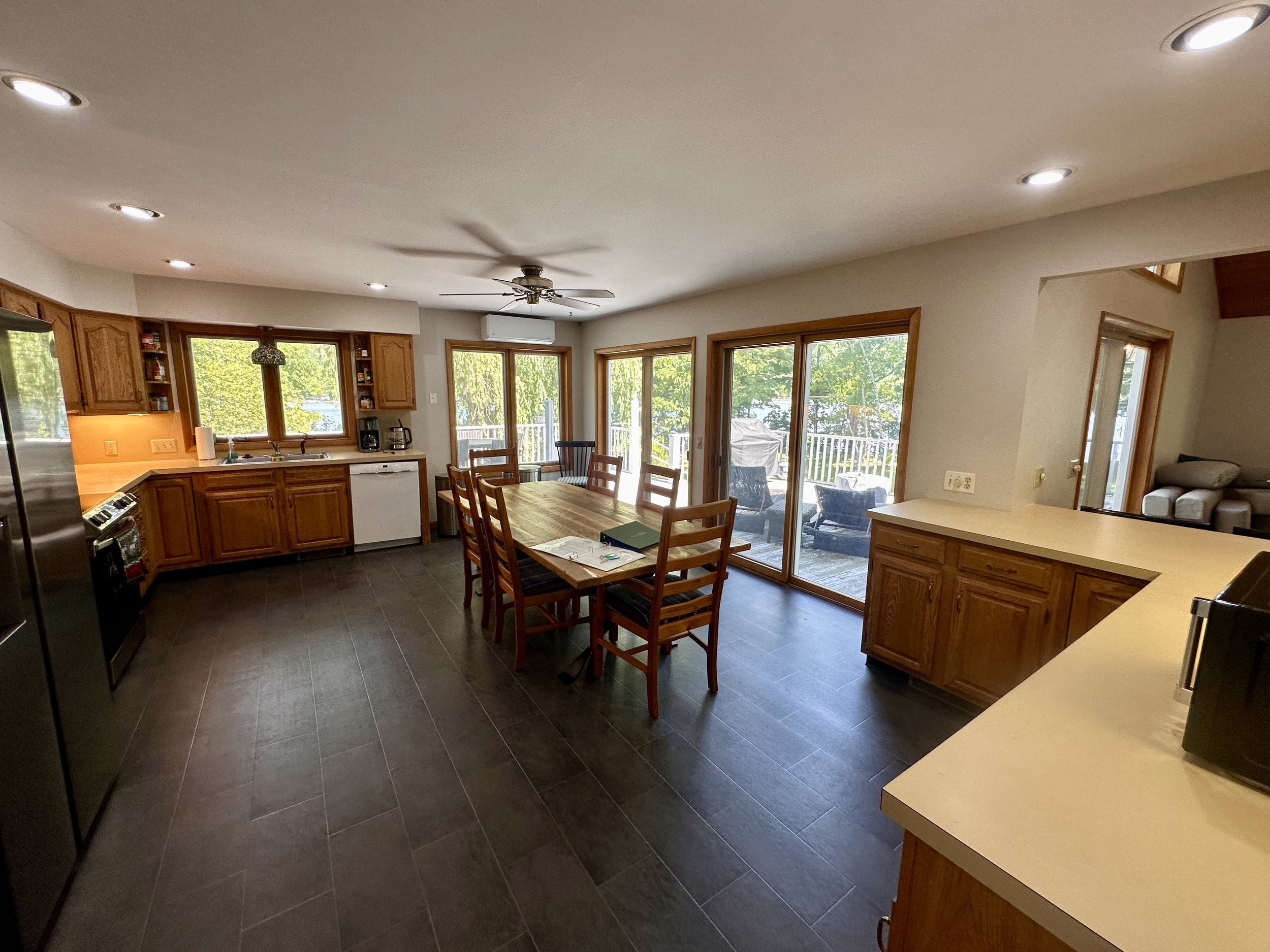 Kitchen and dining area with wooden cabinets, dark tile floor, and sliding glass door leading to an outdoor deck with seating.