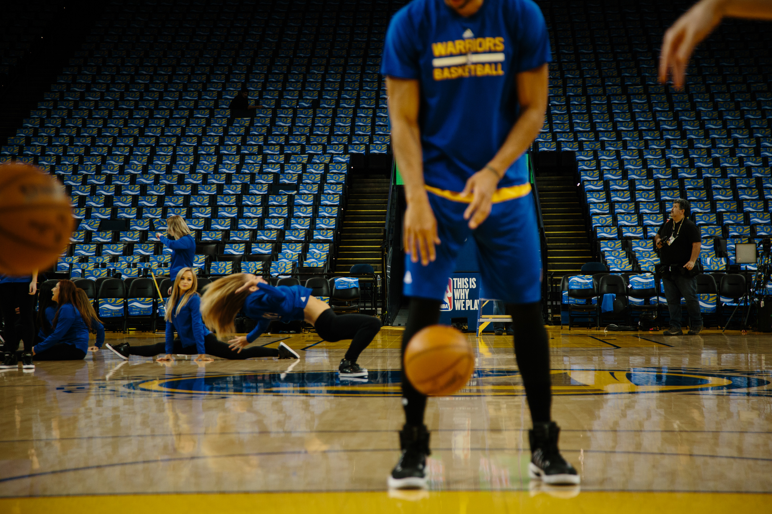  McAdoo warms up before a Warriors home game. In the background, the Warriors dancers practice their dance routine. McAdoo is often the first one on the court warming up; he is so early that technicians are still finishing setting up pyrotechnics and