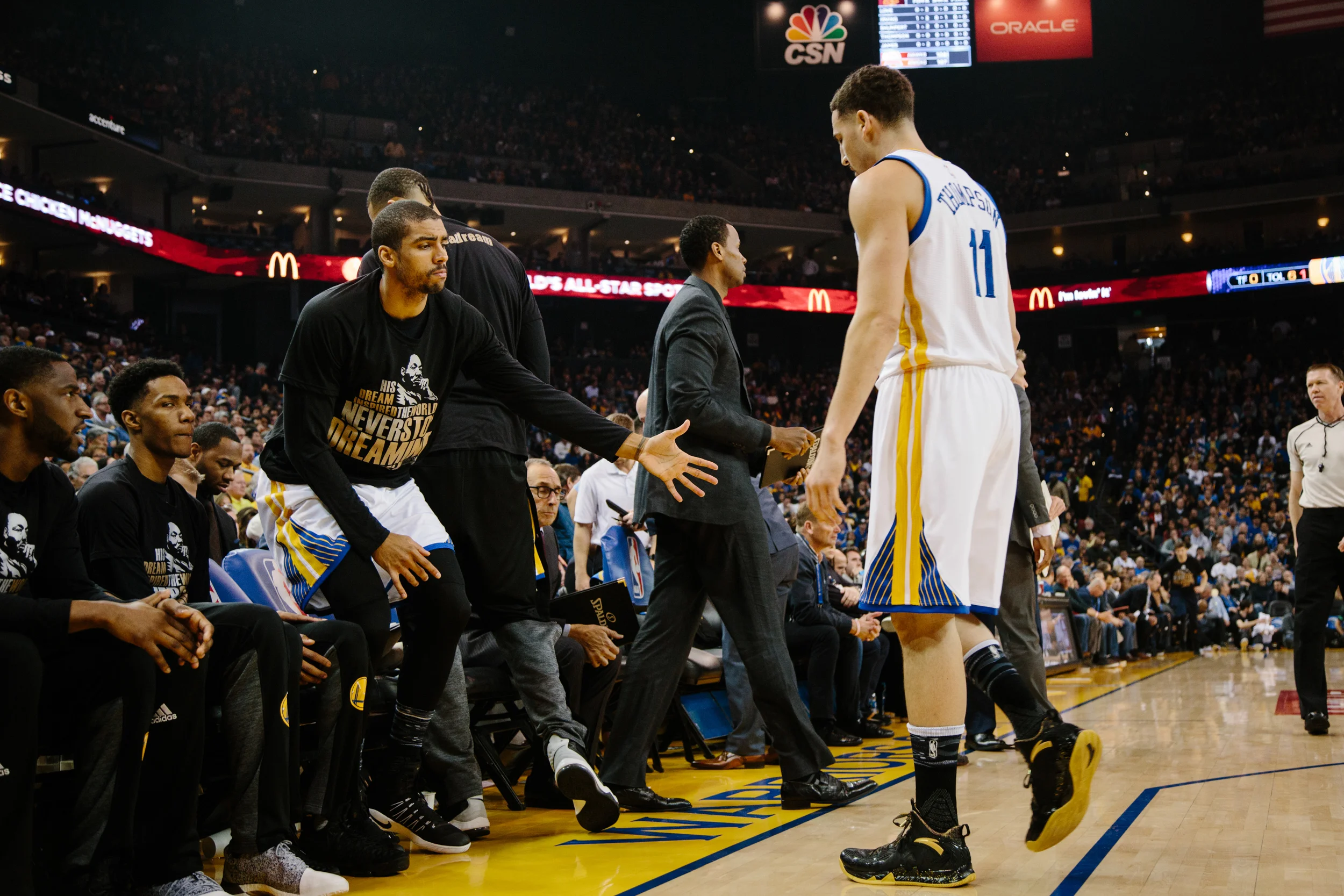 McAdoo watches the Warriors home game against the Cleveland Cavaliers from the bench, high-fiving his teammate Klay Thompson.
