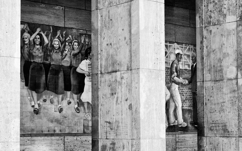CULTURAL REALISM A mural of happy communists graces the side of the current home of the Federal Ministry of Finance in the former East Berlin. The building was built in 1935 as the Reich Ministry of Aviation. During the Cold War it became home to the House of Ministries. The House of Ministries was also part of the demonstrations that took place in June 1953, when the protesters gathered there to demand social reforms and free elections. Hundreds of demonstrators were killed and thousands more were jailed. Several Soviet soldiers were reported to have been executed for their refusal to shoot unarmed demonstrators. Today a monument in front of the ministry commemorates the June uprising.
