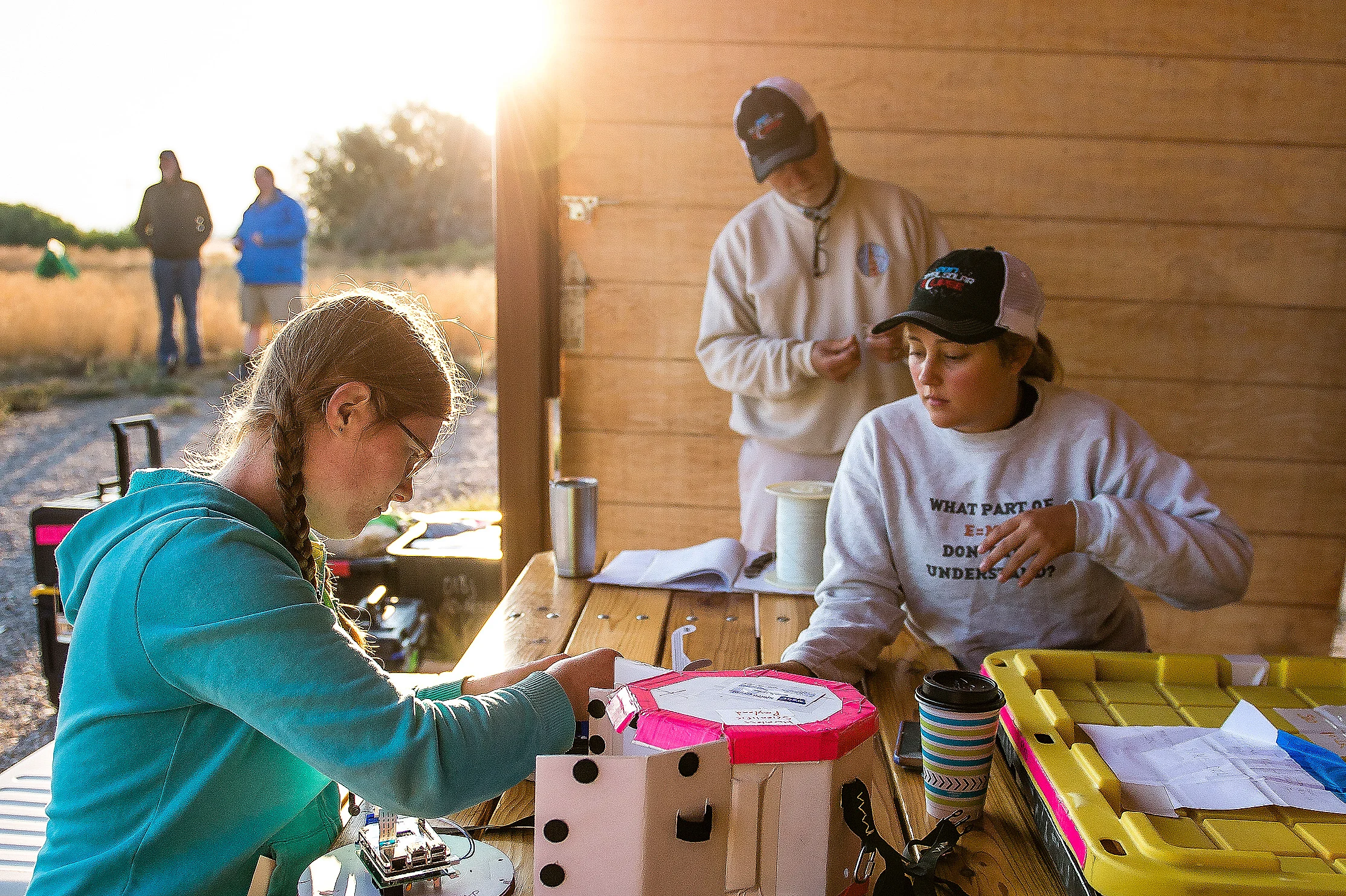 As the sun rises over the MSU team's launch site, team members Katherine Lee, left, and Darci Collins prepare a camera system they designed to capture images of the sun's atmosphere during the eclipse.