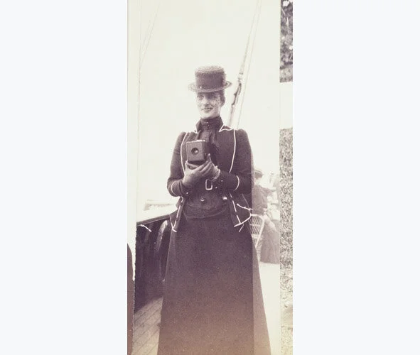 Image: Photograph of the Princess of Wales, later Queen Alexandra, holding a No.1 Kodak camera at chest height. She is standing on the deck of a ship. The No.1 Kodak camera was introduced in 1889 and took small circular photographs. There are many examples of these photographs in Queen Alexandra's album © Royal Collections Trust