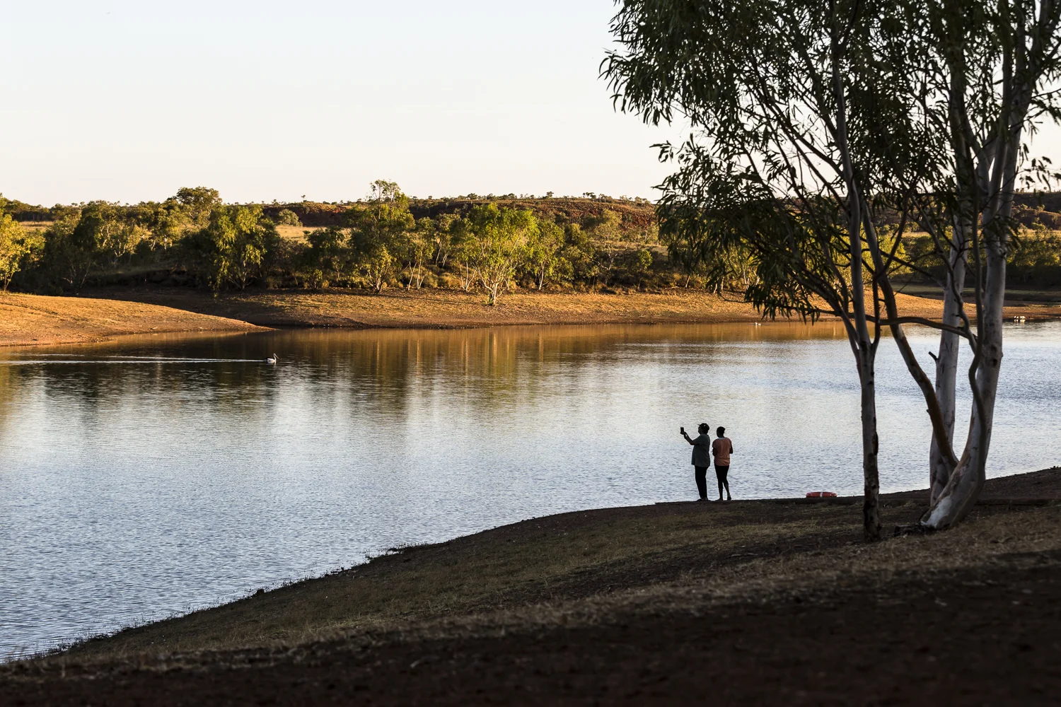 Some friends take photos of a pelican on Lake Mary Ann, the area around the lake is a popular gathering place for local indigenous population.