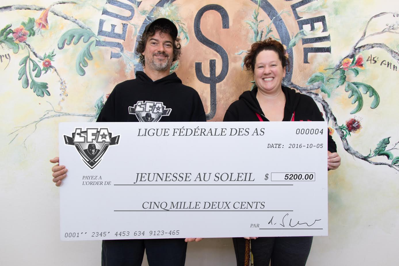 Jean-François DesBois, PDG de la LFA, remettant un chèque de 5200$ à Kara De La Peralle de Jeunesse au Soleil. Les fonds ont été recueillis lors du Match de Championnat estival 2016 et serviront à financer le programme de développement hockey SLAP de la fondation.