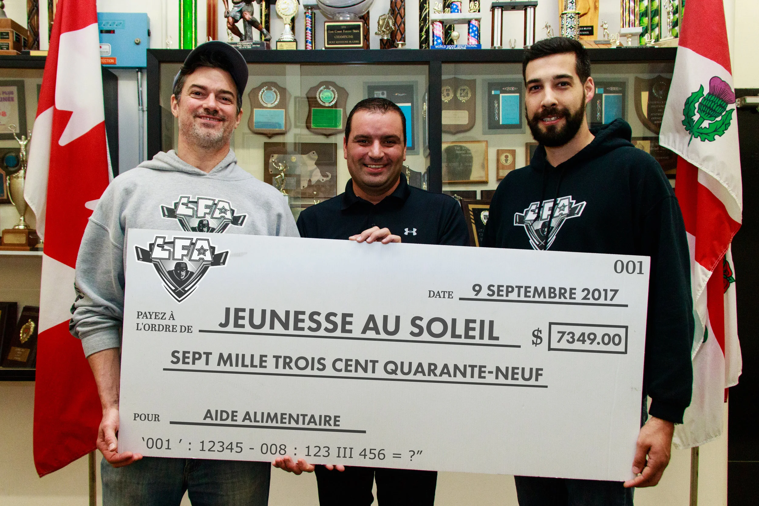 MONEY RAISED FOR THE SUN YOUTH FOOD BANK DURING THE LFA'S SUMMER CHAMPIONSHIP GAME AUGUST 27TH (FROM LEFT TO RIGHT) THE CEO OF THE LFA JEAN-FRANCOIS DESBOIS WITH HEILO GALEGO FROM SUN YOUTH AND JACOB POLIQUIN THE DIRECTOR OF COMMUNICATIONS OF THE LEAGUE ,(PHOTO JOE FLEMINGS),