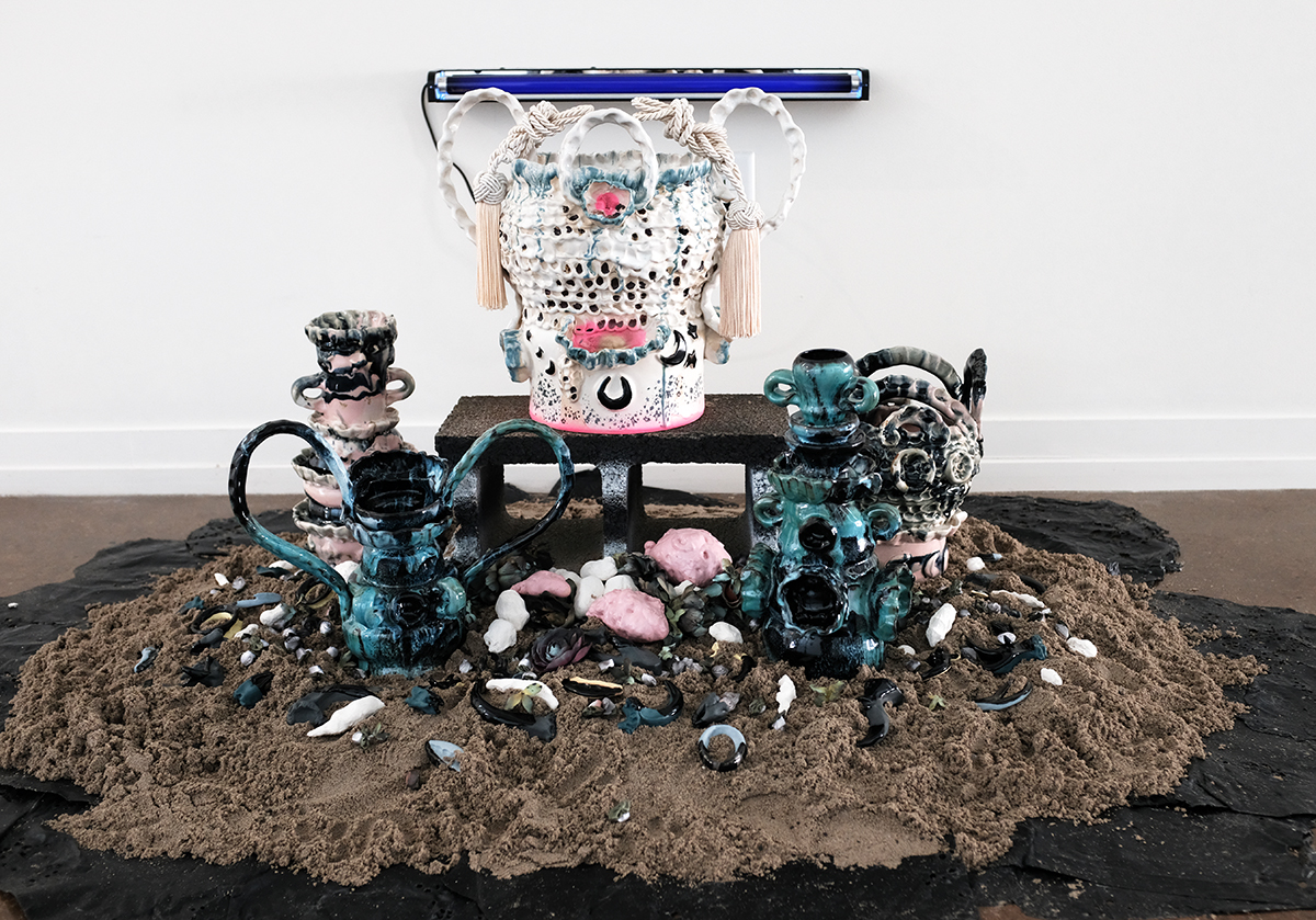 Zipporah Thompson, blue haze equinox, 2019, stoneware, oxides, glazes, wax, faux flowers, ribbon, foam, paint, sand, rubber mulch, cinder block, blacklight