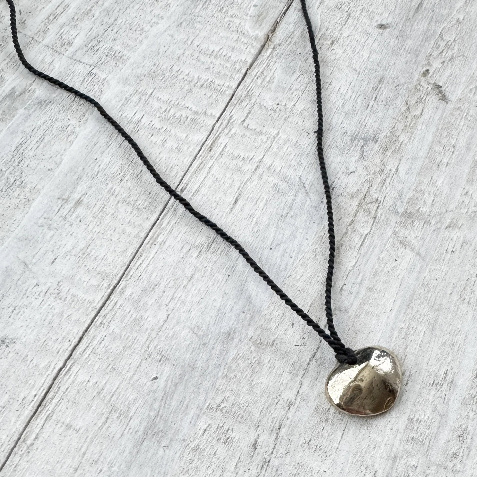brass coin pendant on black cord