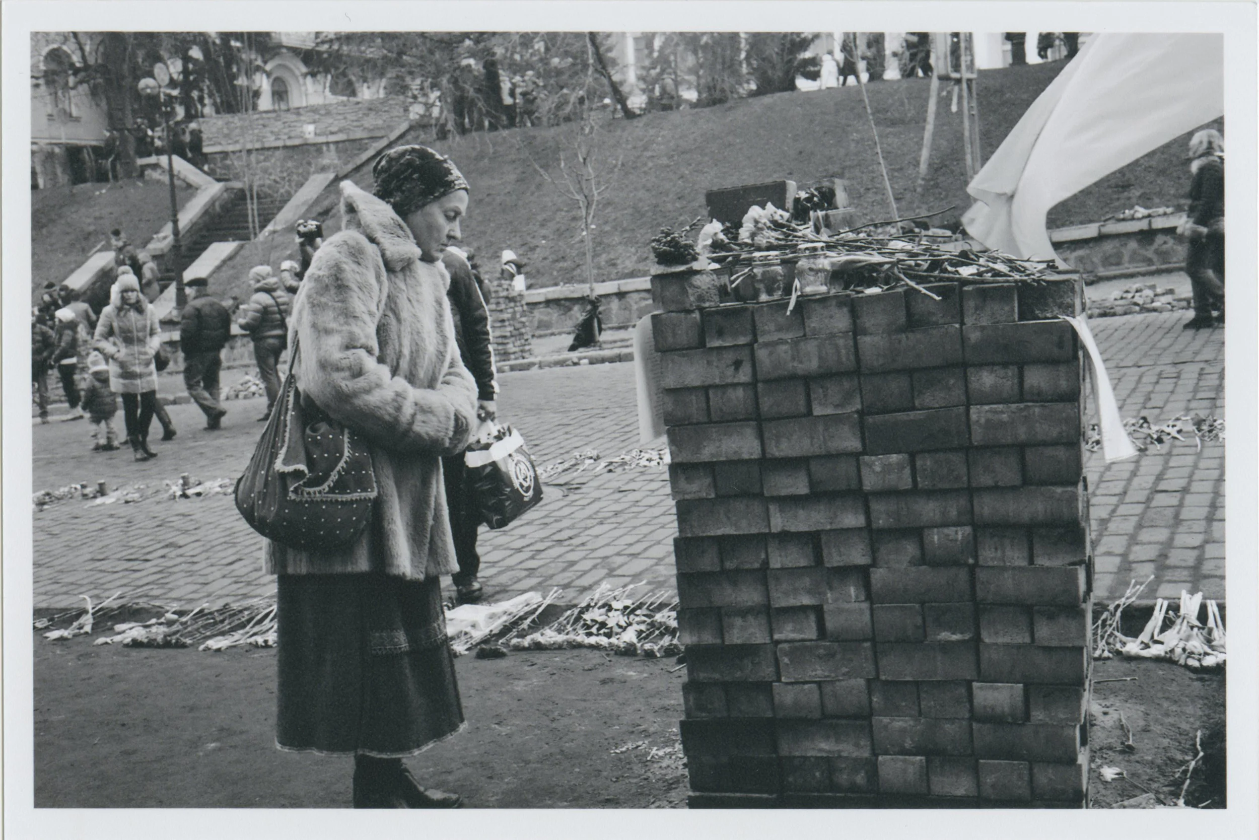 A woman standing next to a newly made brick wall, made from the stones in the street. Where there is dirt in this picture, there once was a beautiful stone road. Behind here, you can see a flower path. There was a flower road leading up the street where 76 people were killed by government snipper fire. Photo: Michael Berlucchi