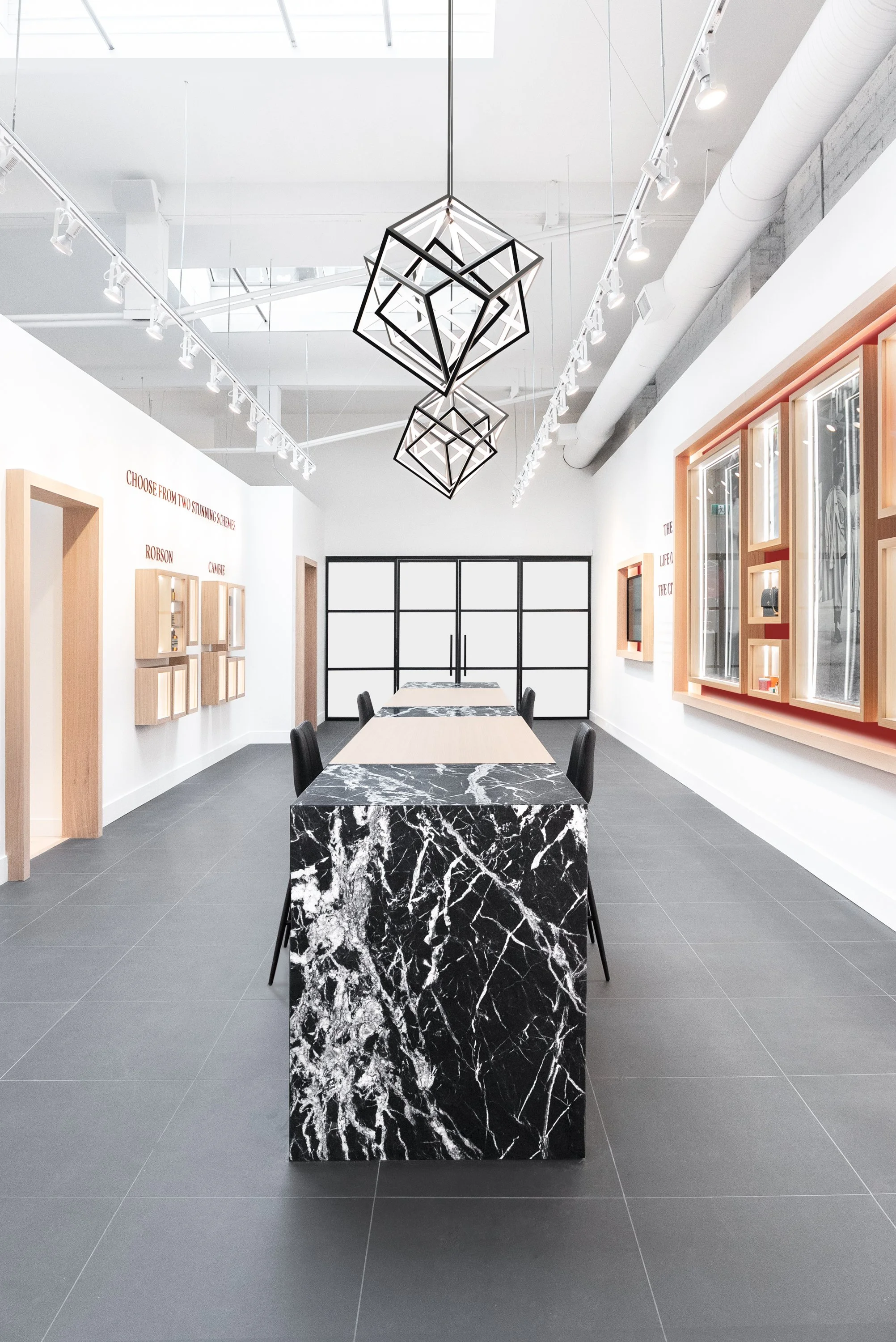 Modern conference room with black marble tables, black chairs, geometric ceiling lights, and display shelves on white walls.