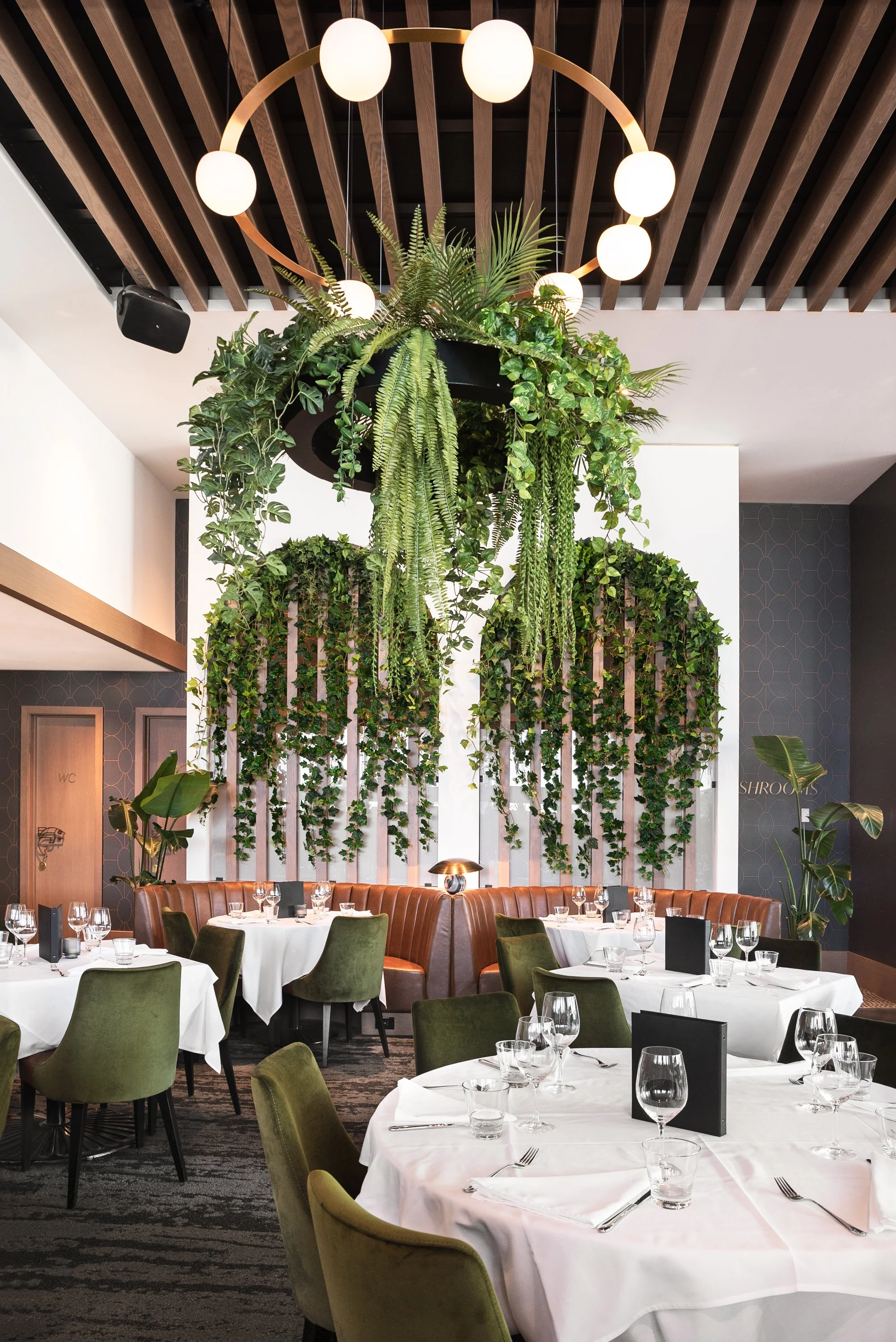 Interior of a restaurant with hanging greenery and a modern chandelier.