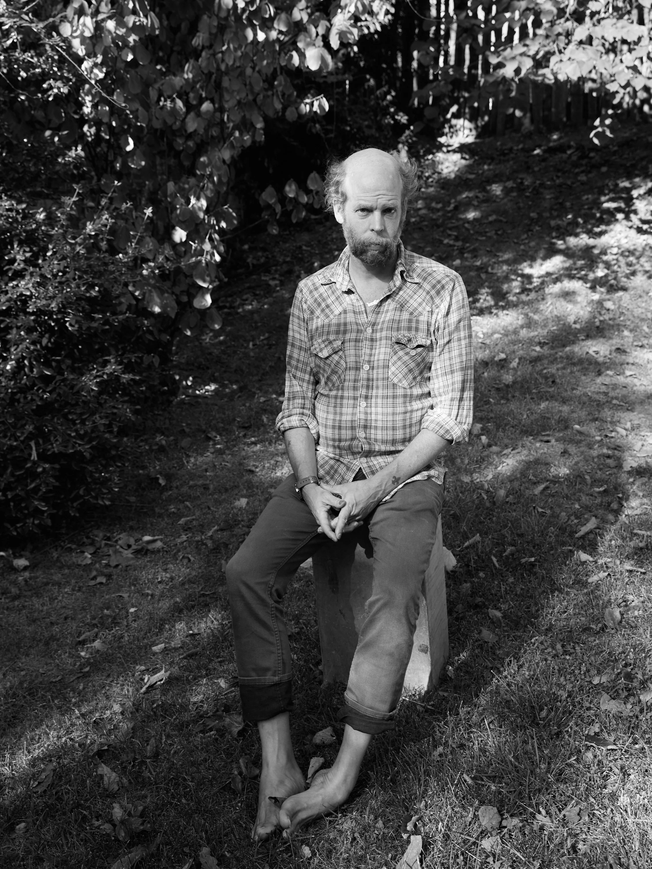 A black-and-white photo of a person holding a small dog in their lap outdoors.
