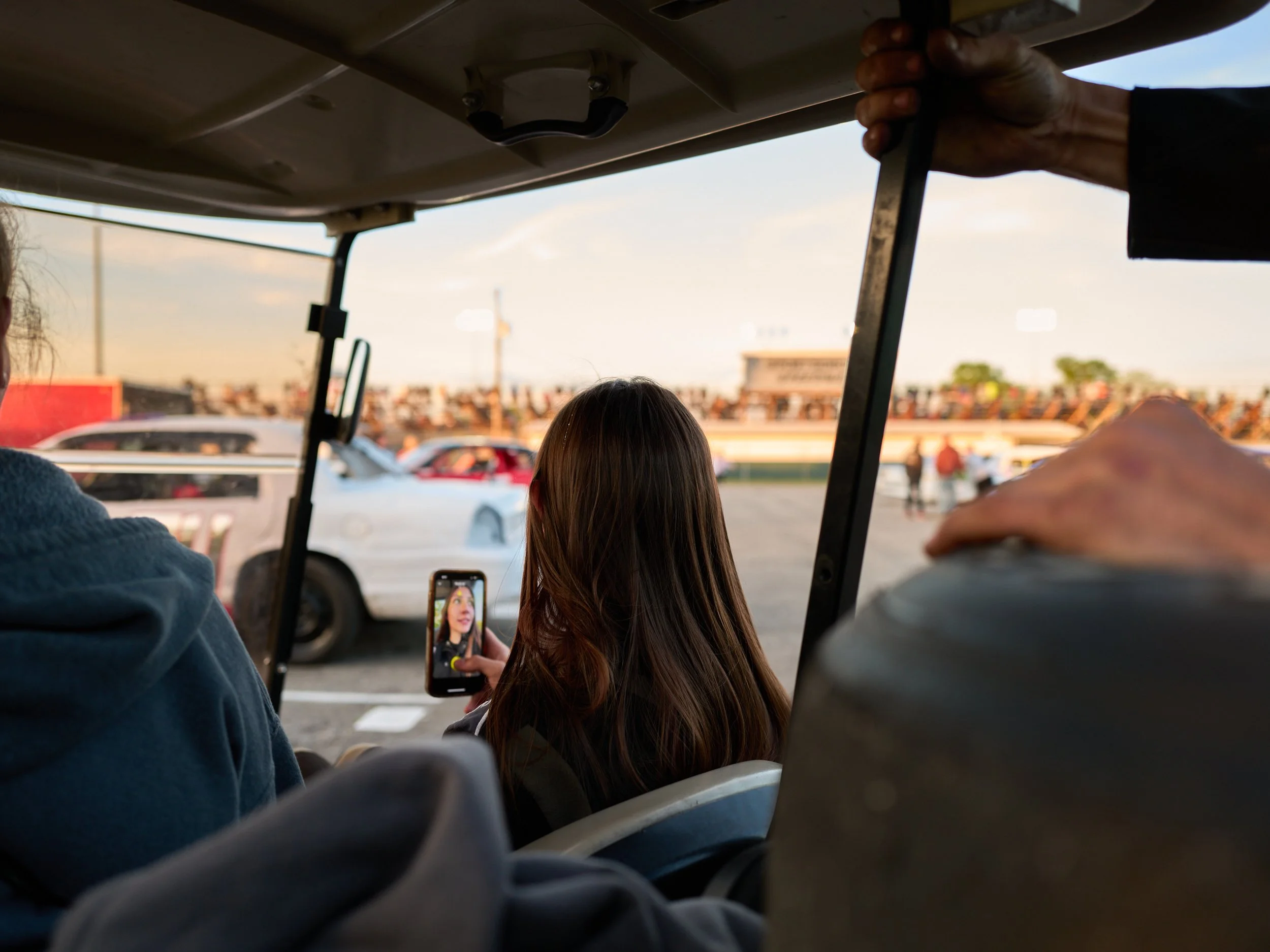 People sitting and taking a photo at a racetrack during a sunset