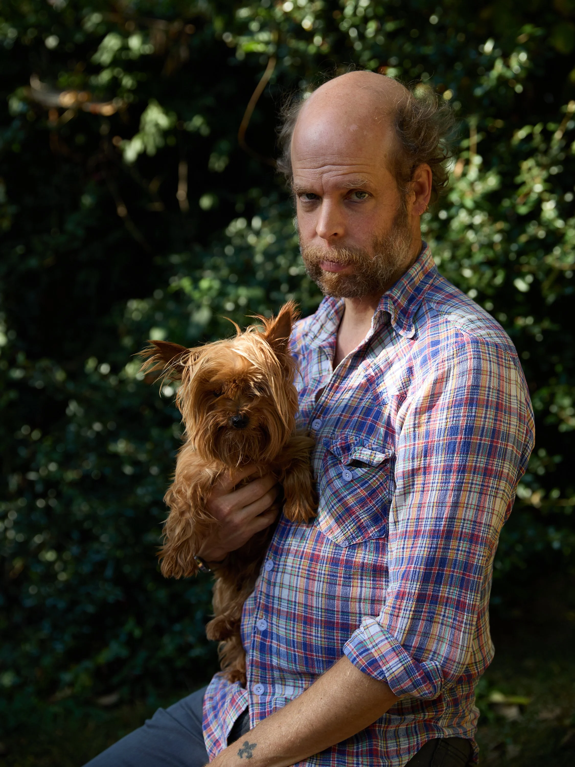 A photo of a person holding a small dog in their lap outdoors.